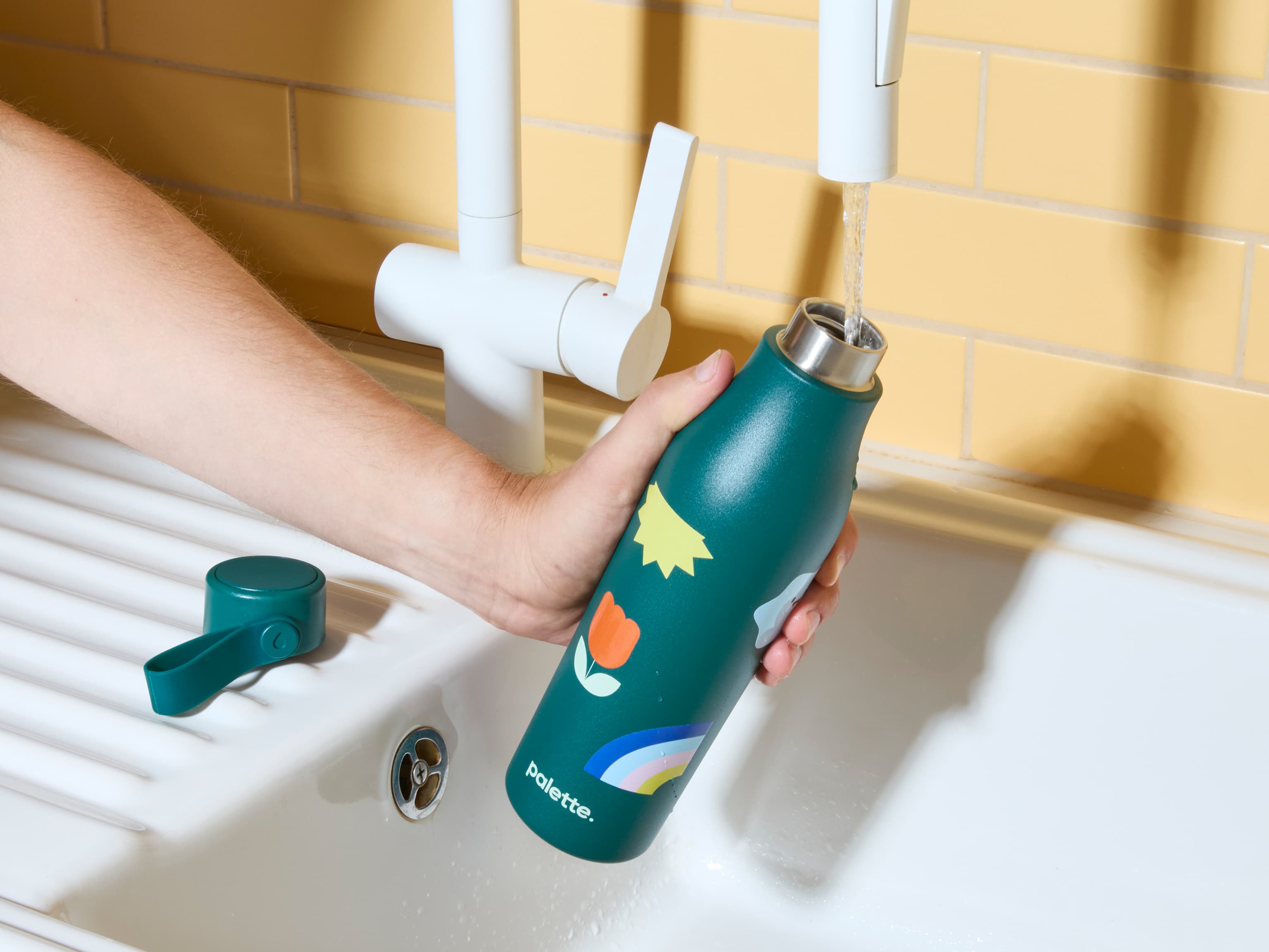 Someone filling a green custom water bottle from a tap.