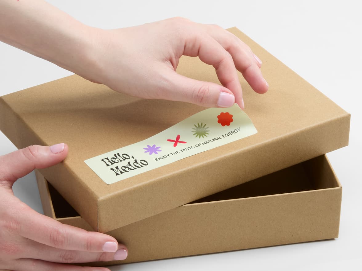 A person placing a matte paper sticker in size 1.5x55 on a cardboard box.