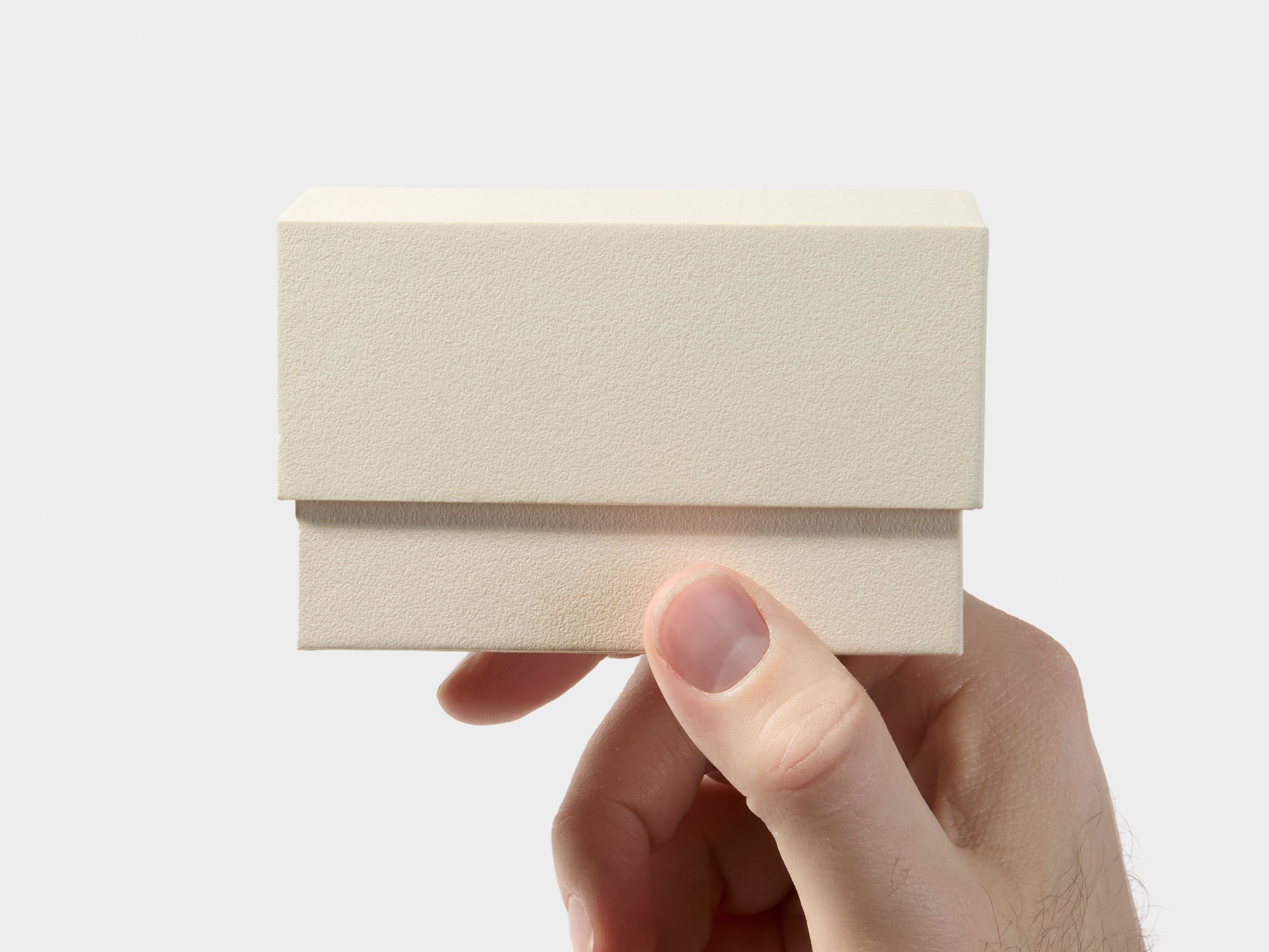 A hand holding an off white business card box.