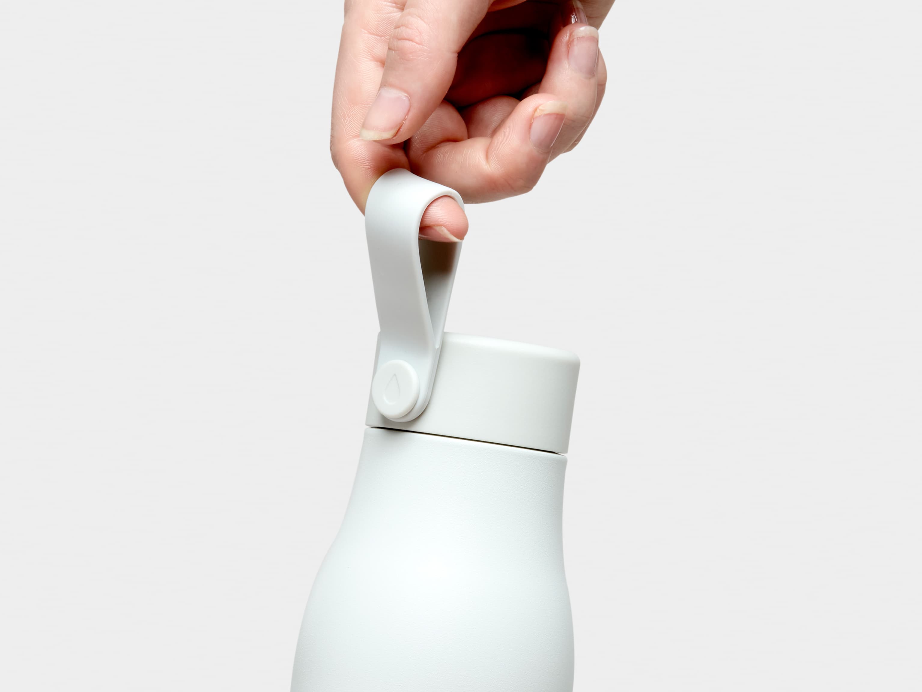 A close up of a person holding a cloudy grey MOO water bottle by the top strap.