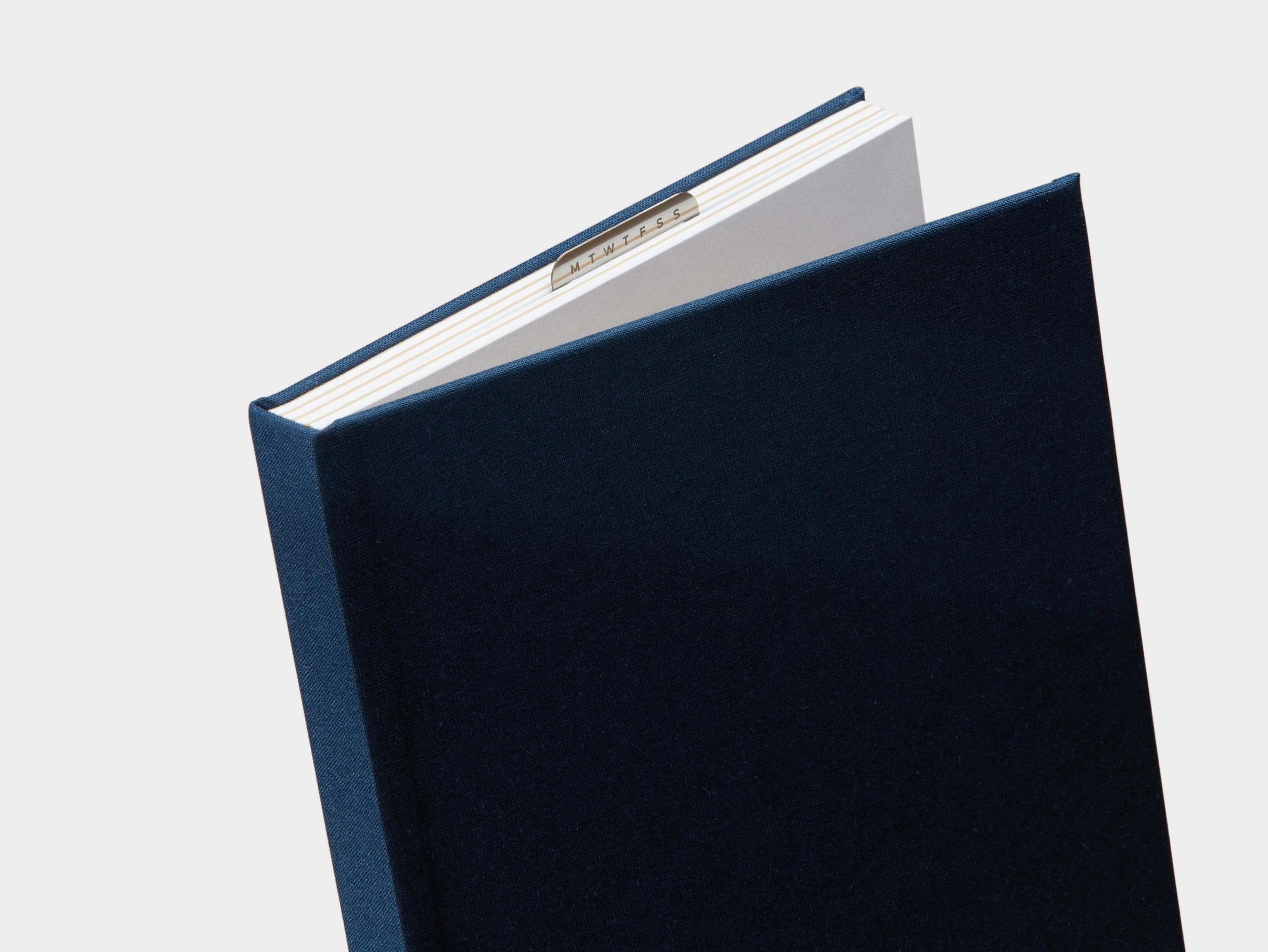 Half Opened Midnight Blue  Cloth Planner with a silver clip sticking out