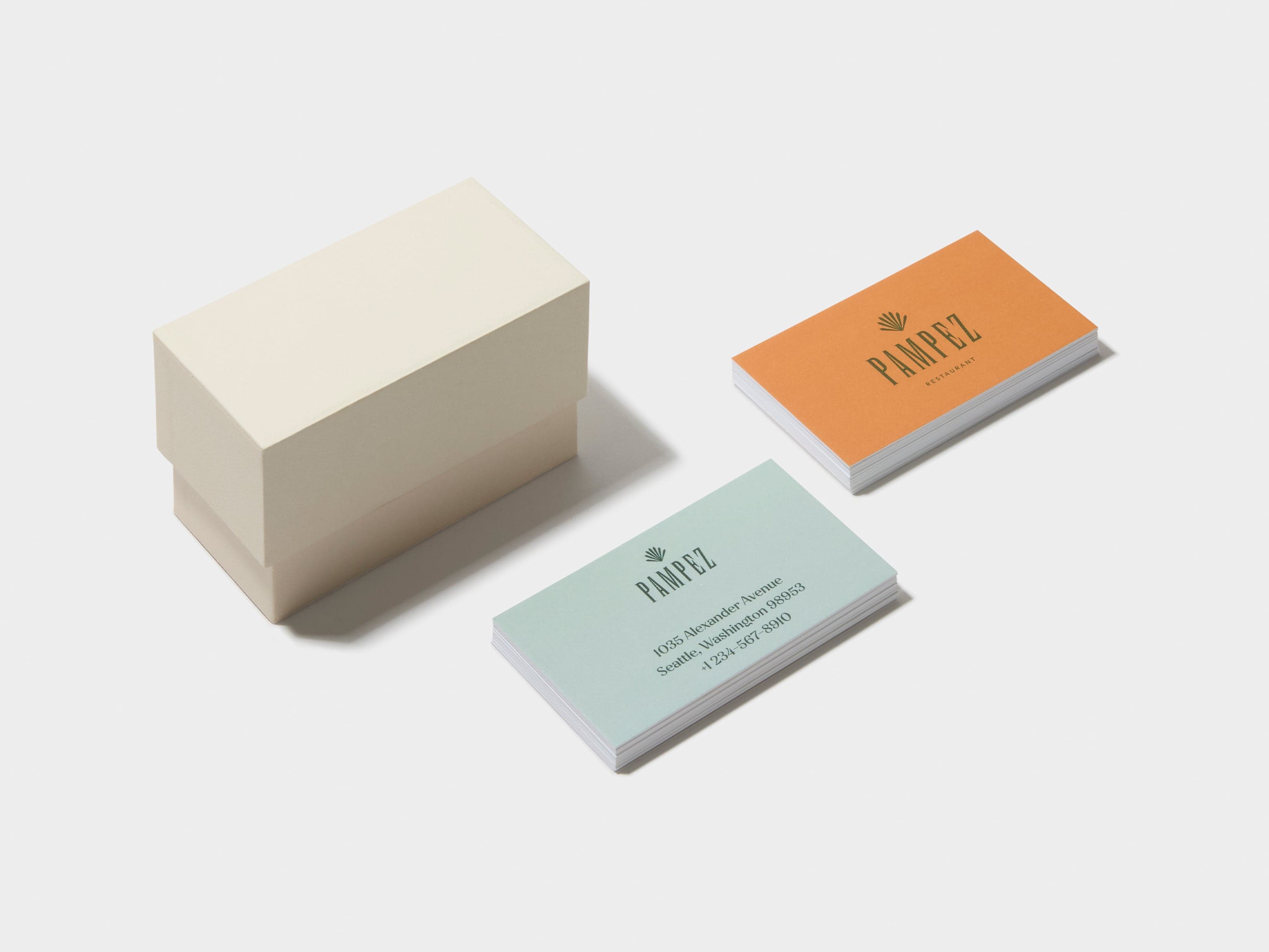 A closed off white business card box with two piles of customised luxe business cards placed near it.