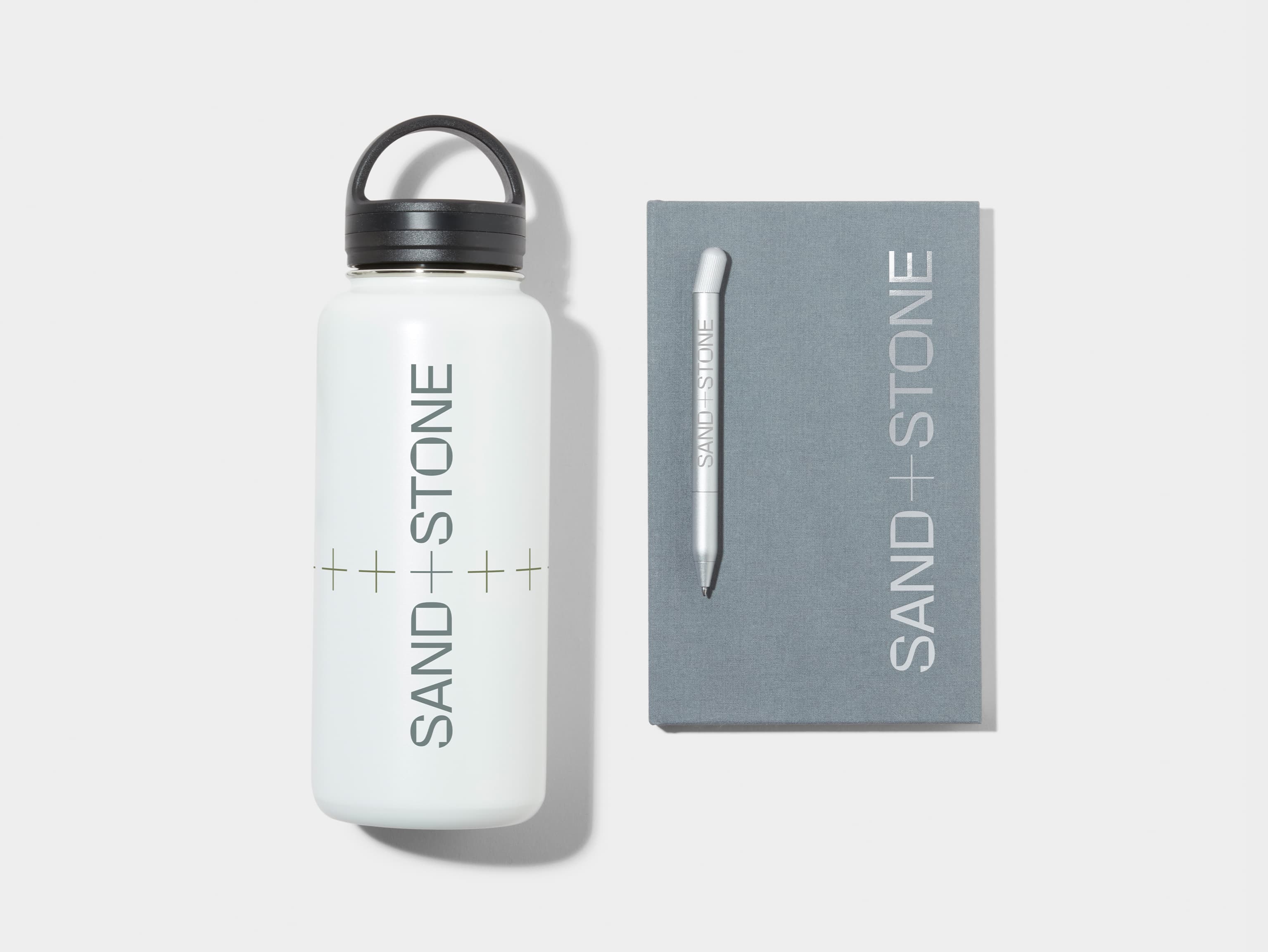 Large Insulated Water Bottle in Cloudy Grey with 360 wrap printing customisation next to a Cloudy Grey Hard Cover Notebook and MOO Twist Pen with custom branding