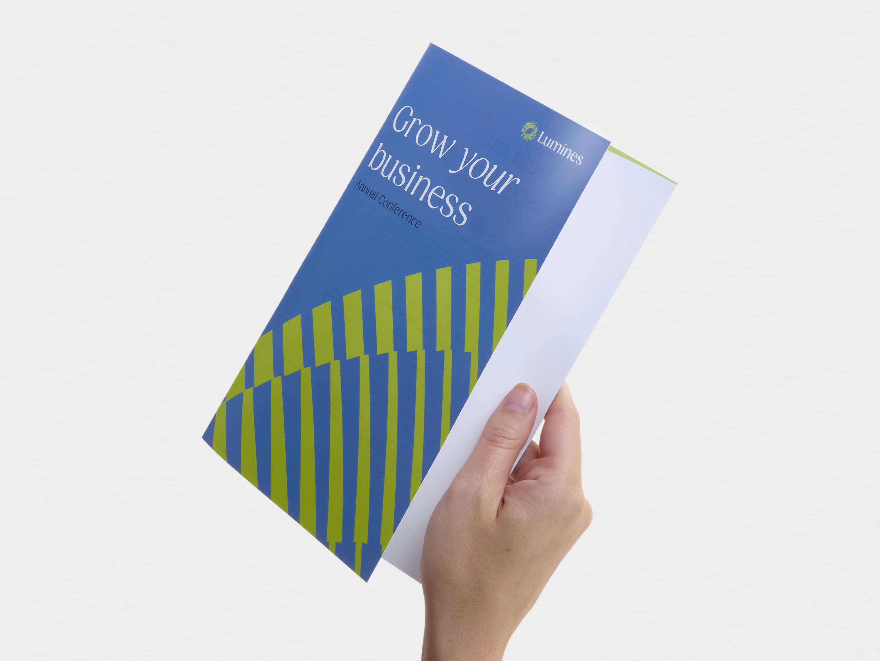 A hand holding a bi-fold gloss paper brochure.