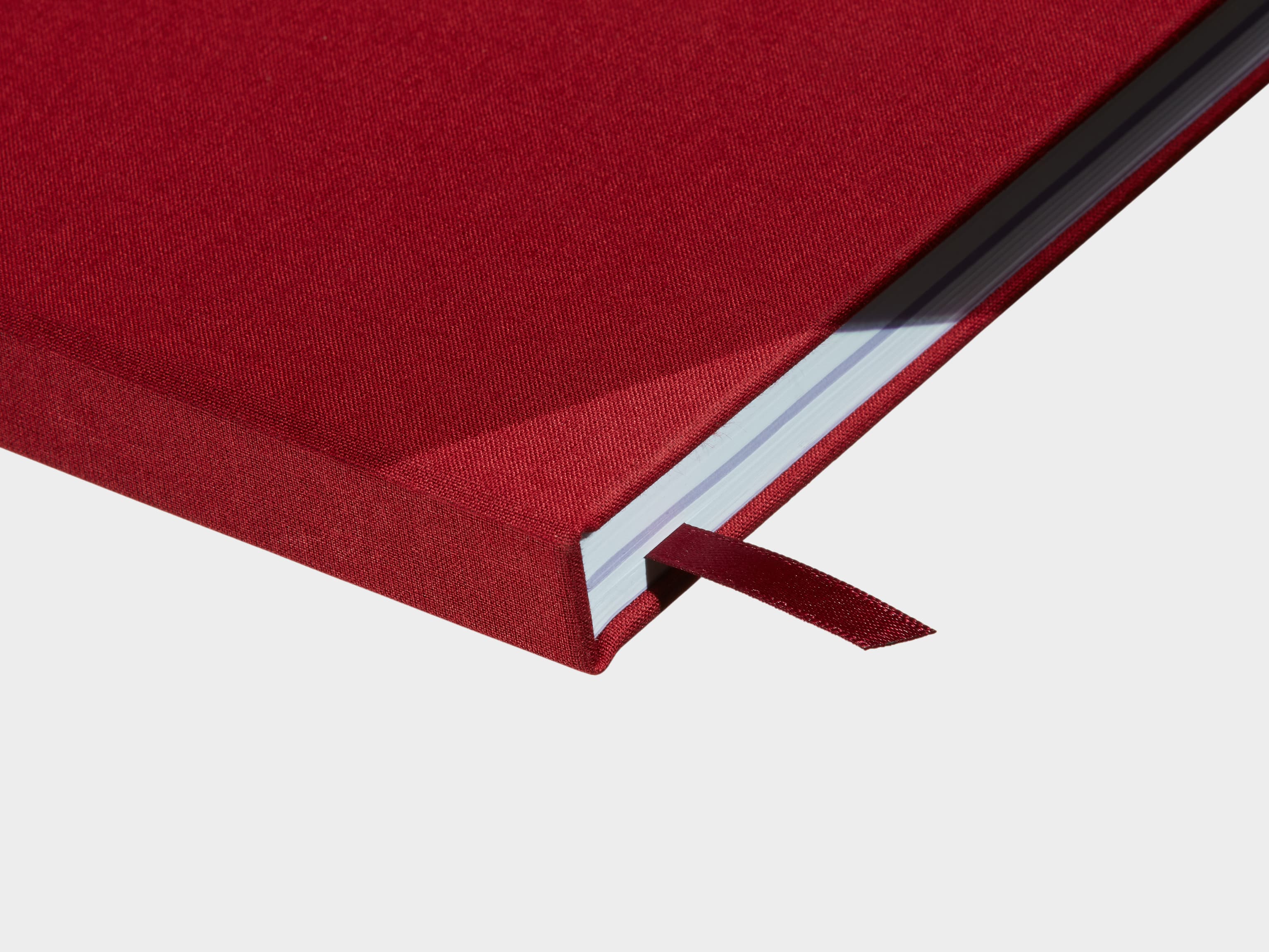 A close up of a closed Wine Red Hardcover Notebook with a red ribbon sticking out