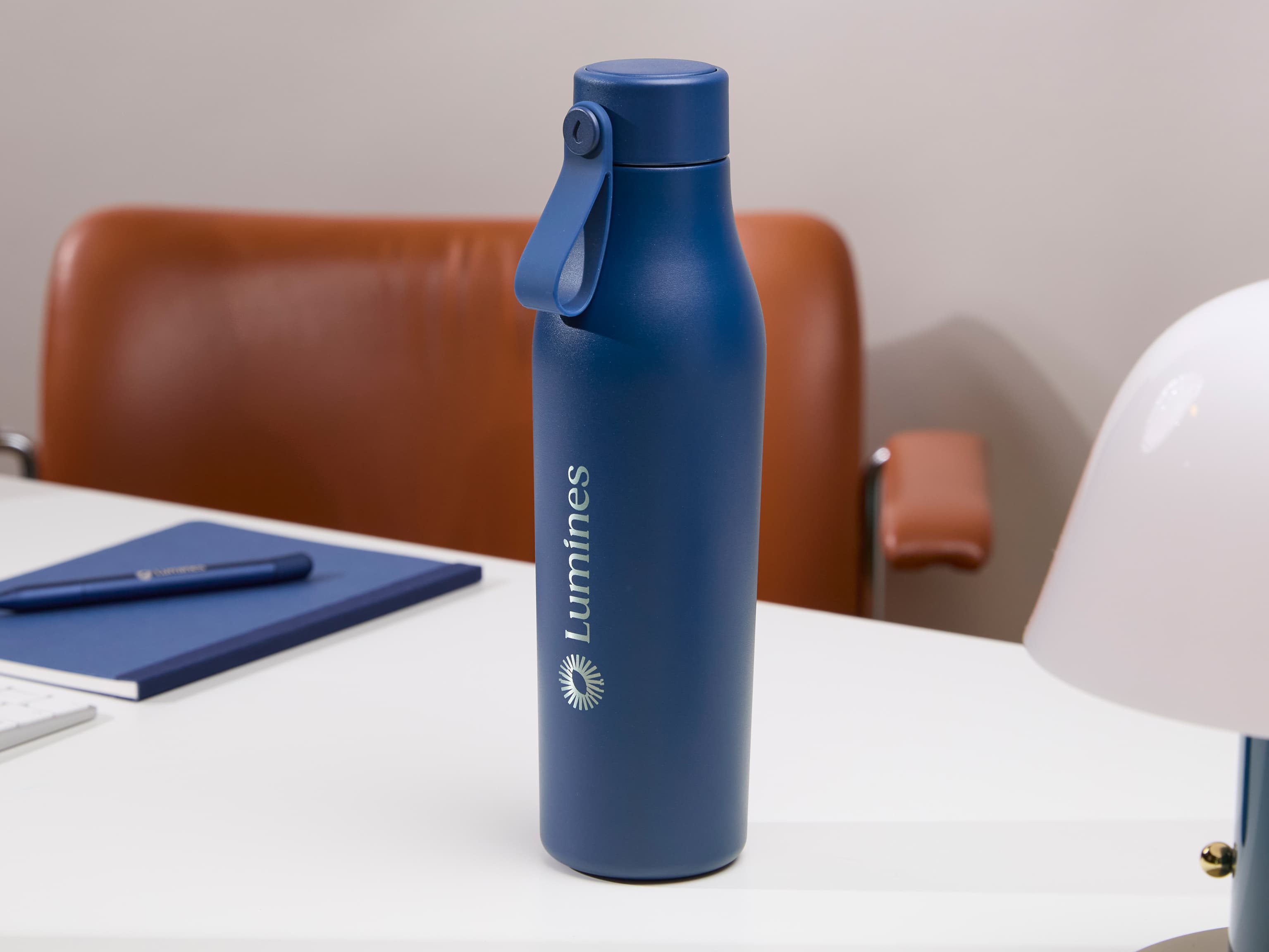 A blue water bottle with custom silver branding.