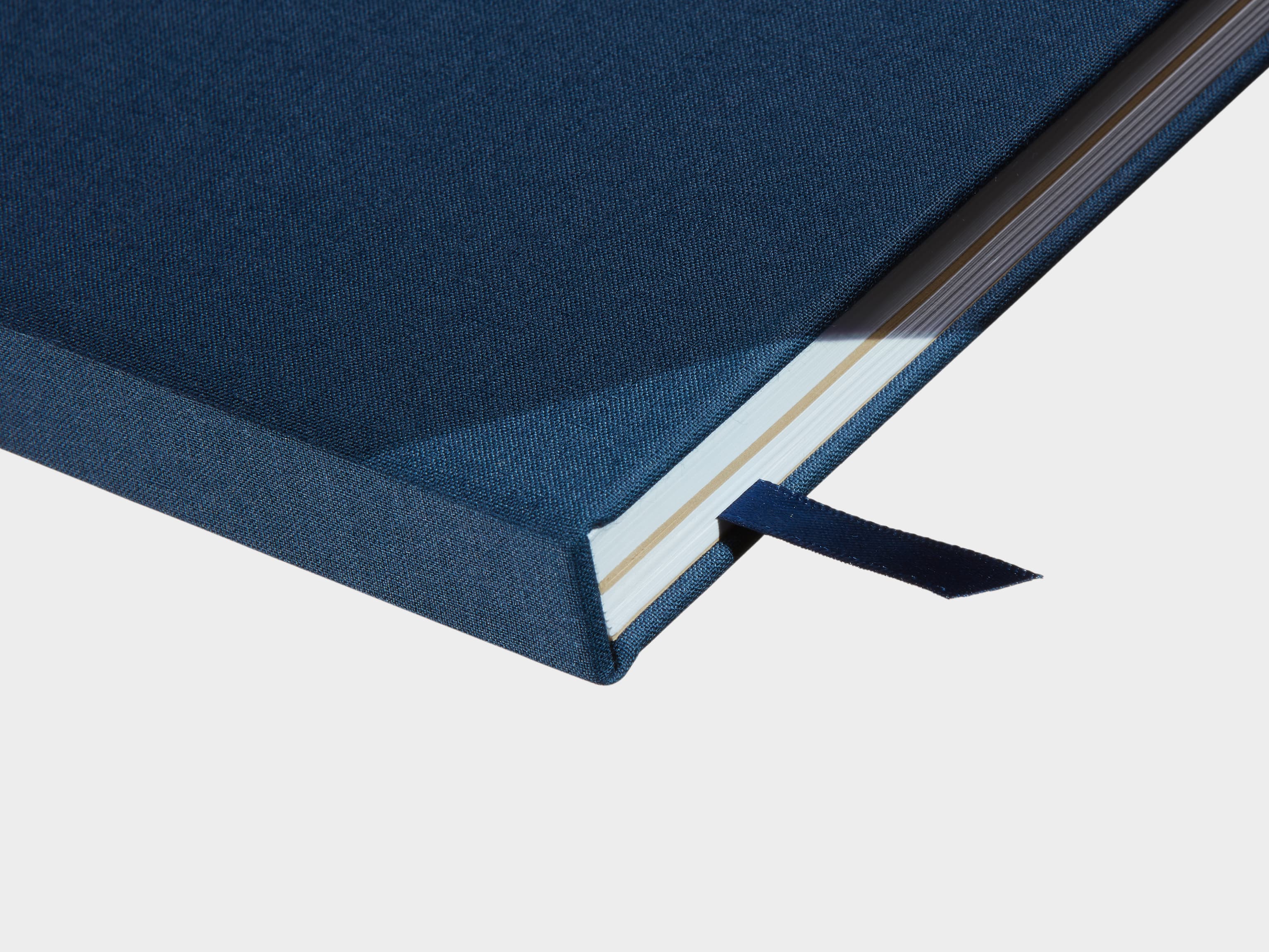 A close up of a closed Midnight Blue Hardcover Notebook with a green ribbon sticking out