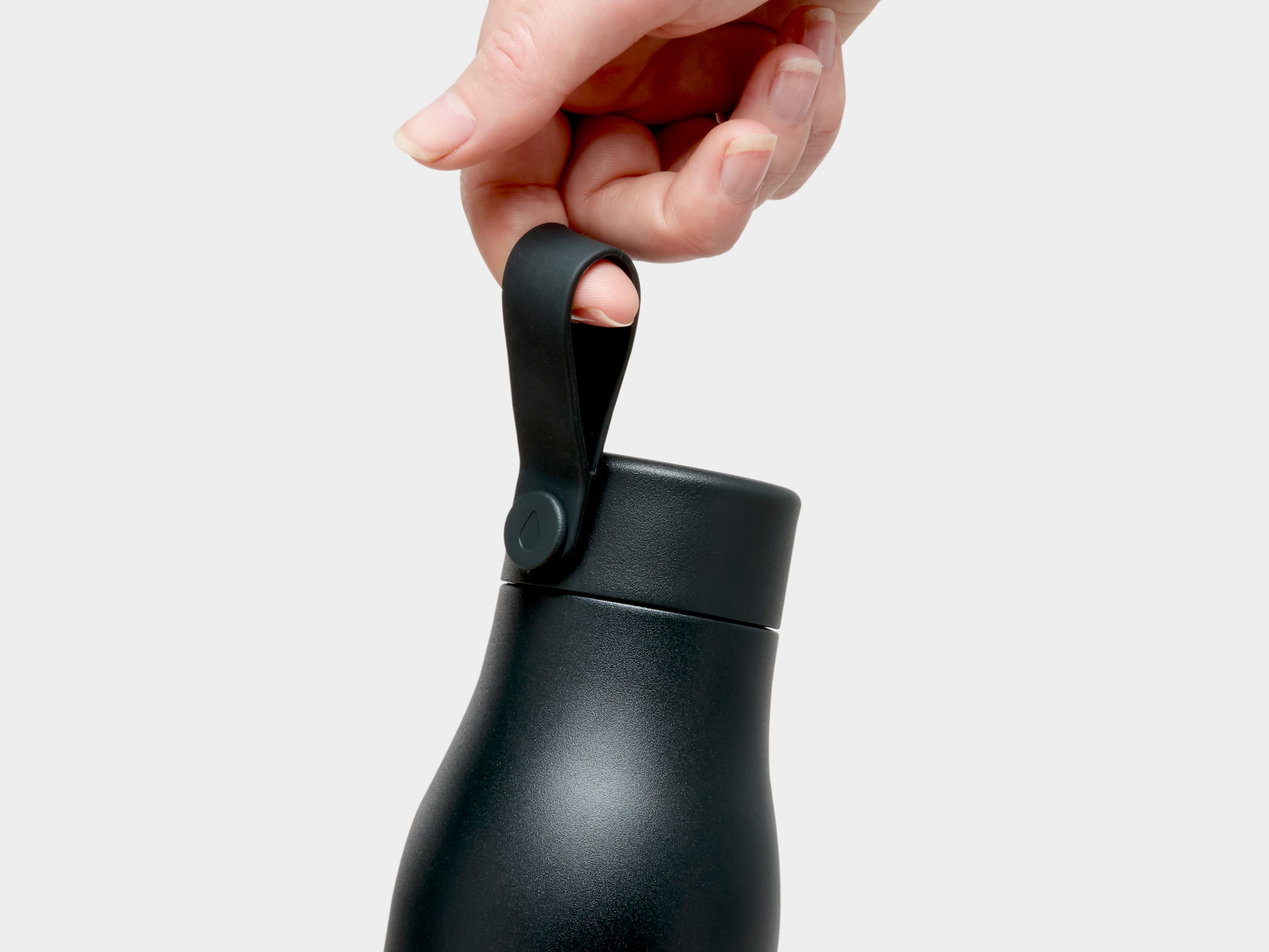 A close up of a person holding a jet black MOO water bottle by the top strap.