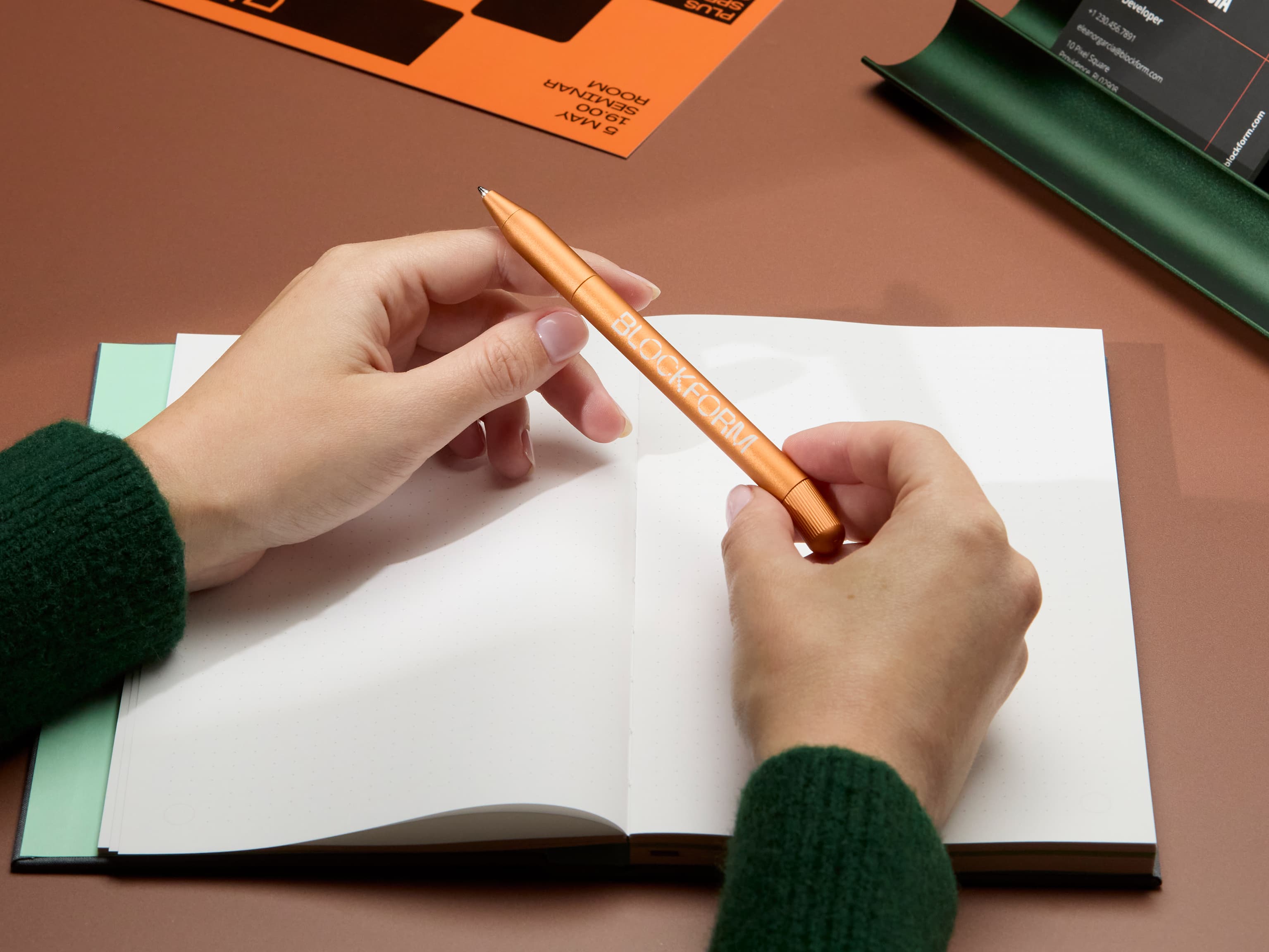 A person holding a custom orange pen.