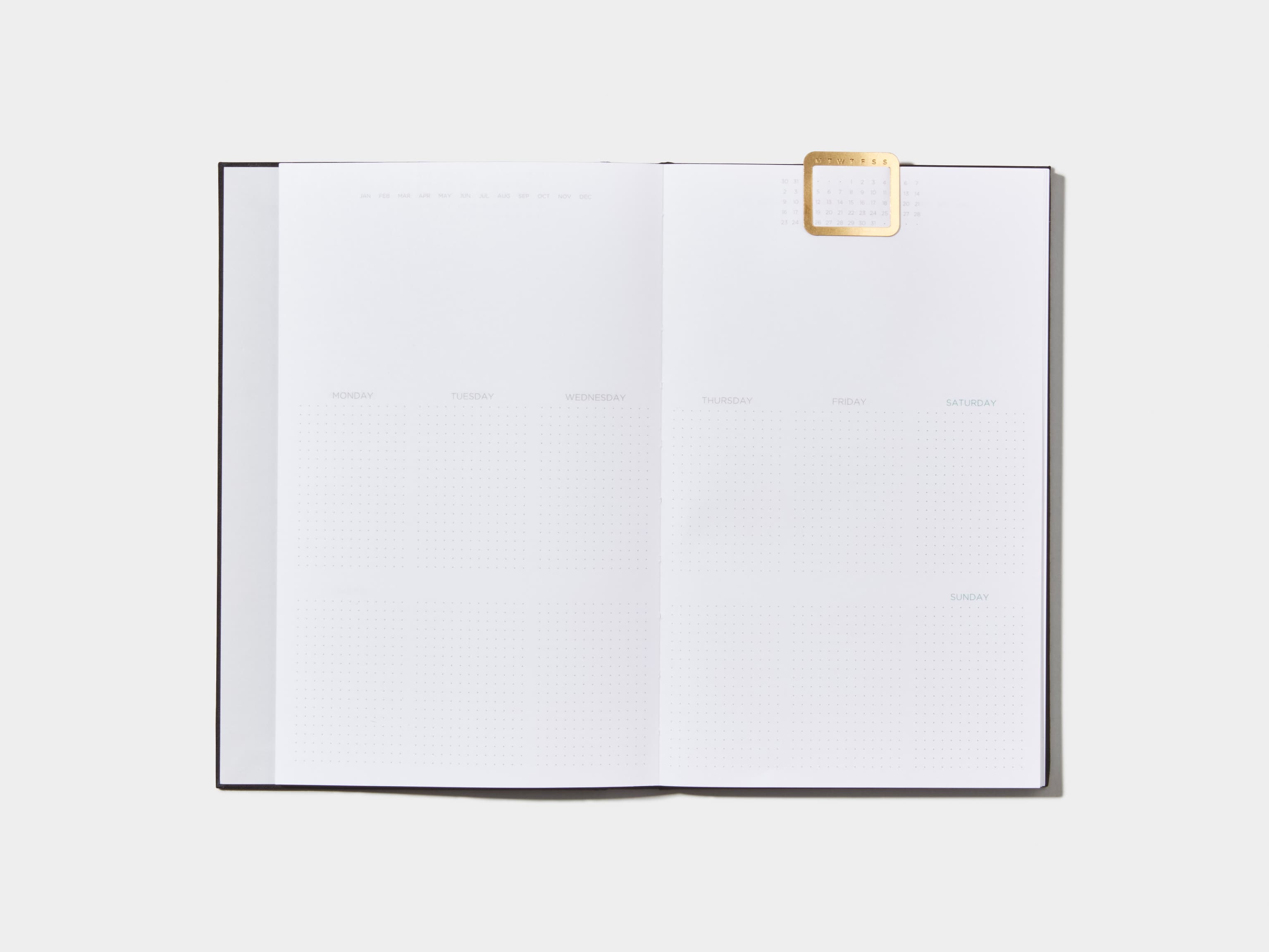 Opened Jet Black  Cloth Planner with a calendar page inside and a gold clip 