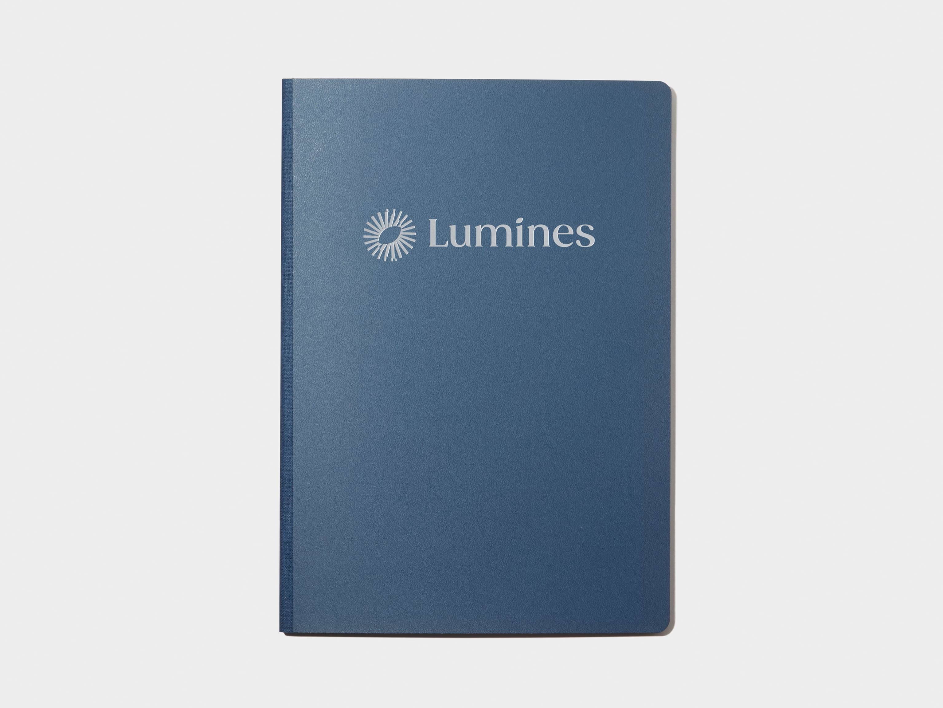 A blue softcover planner with custom branding in silver foil.