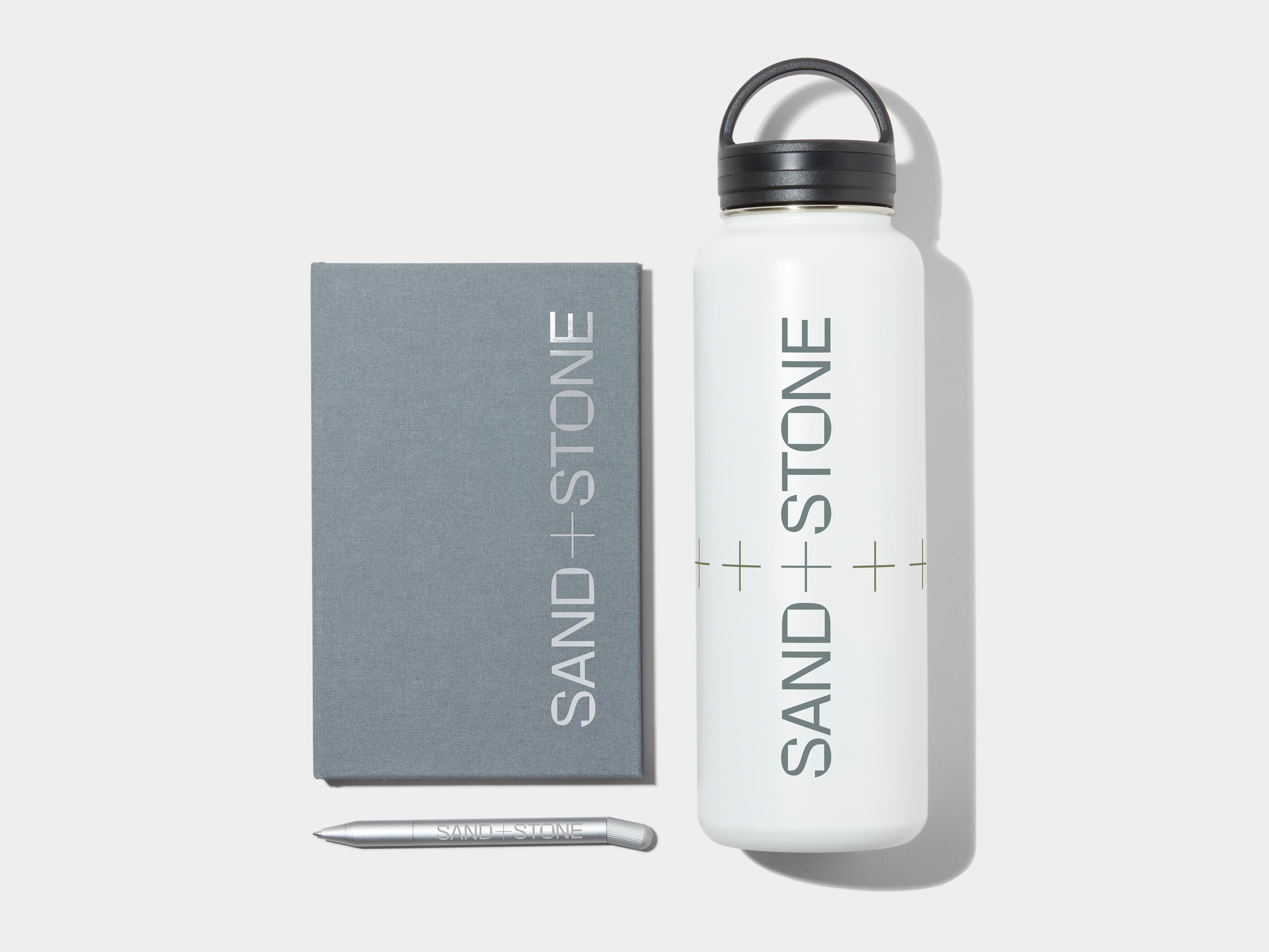 XL Insulated Water Bottle in Cloudy Grey with 360 wrap printing customisation next to a Cloudy Grey Hard Cover Notebook and MOO Twist Pen with custom branding