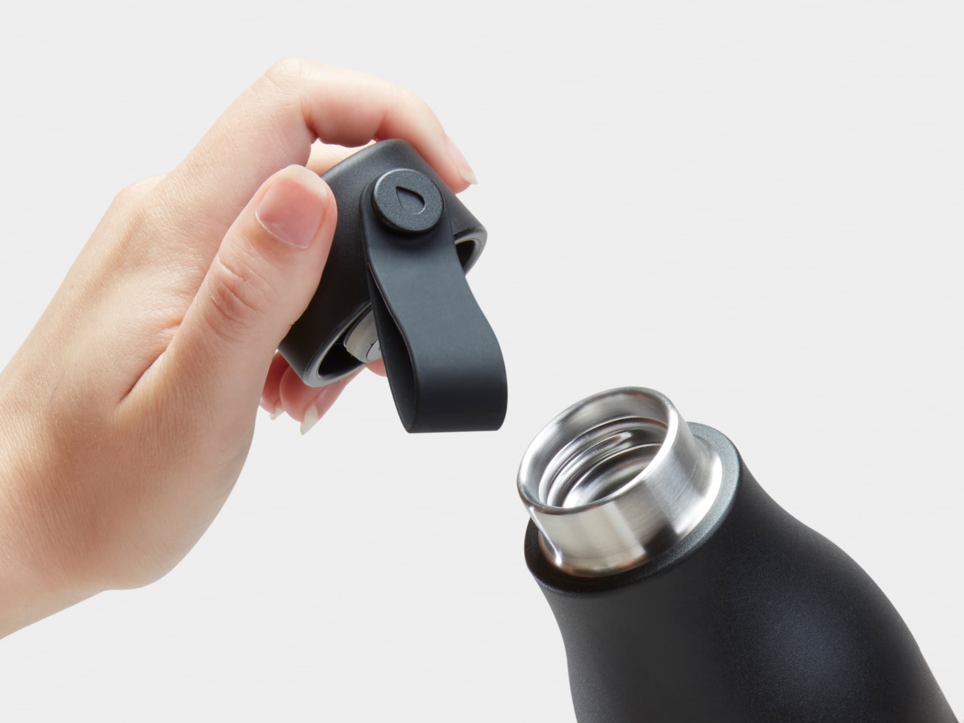 The top of a black water bottle with someone holding the lid.