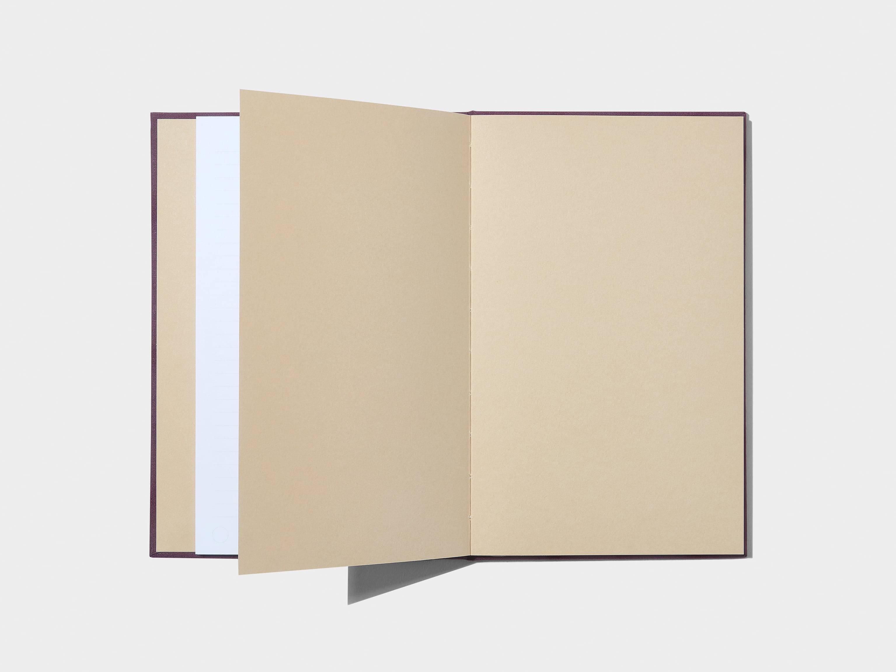 A mulberry coloured hardcover notebook laid flat open displaying tan and white coloured pages.