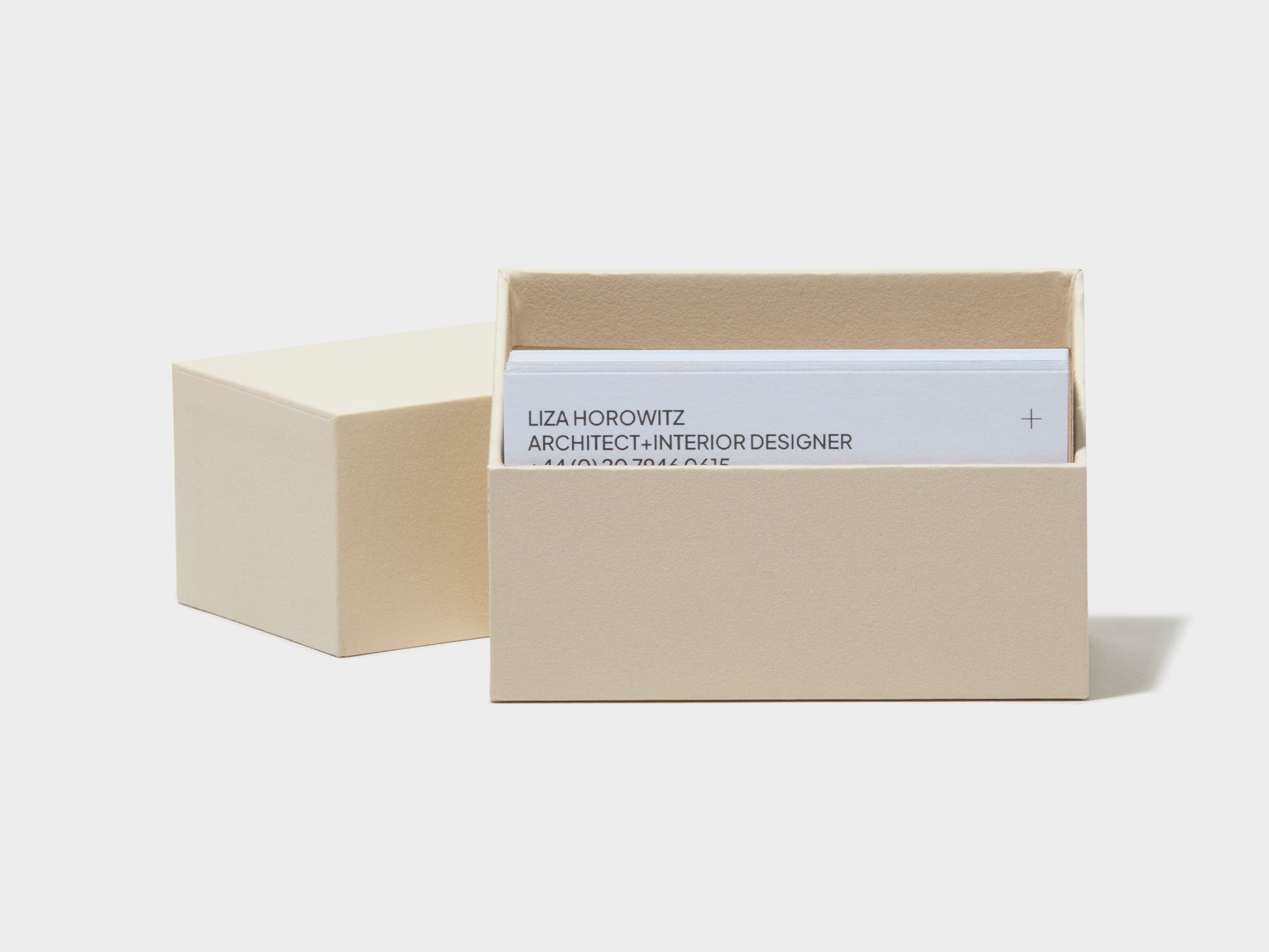 An off white business card box with custom white luxe business cards placed inside it.