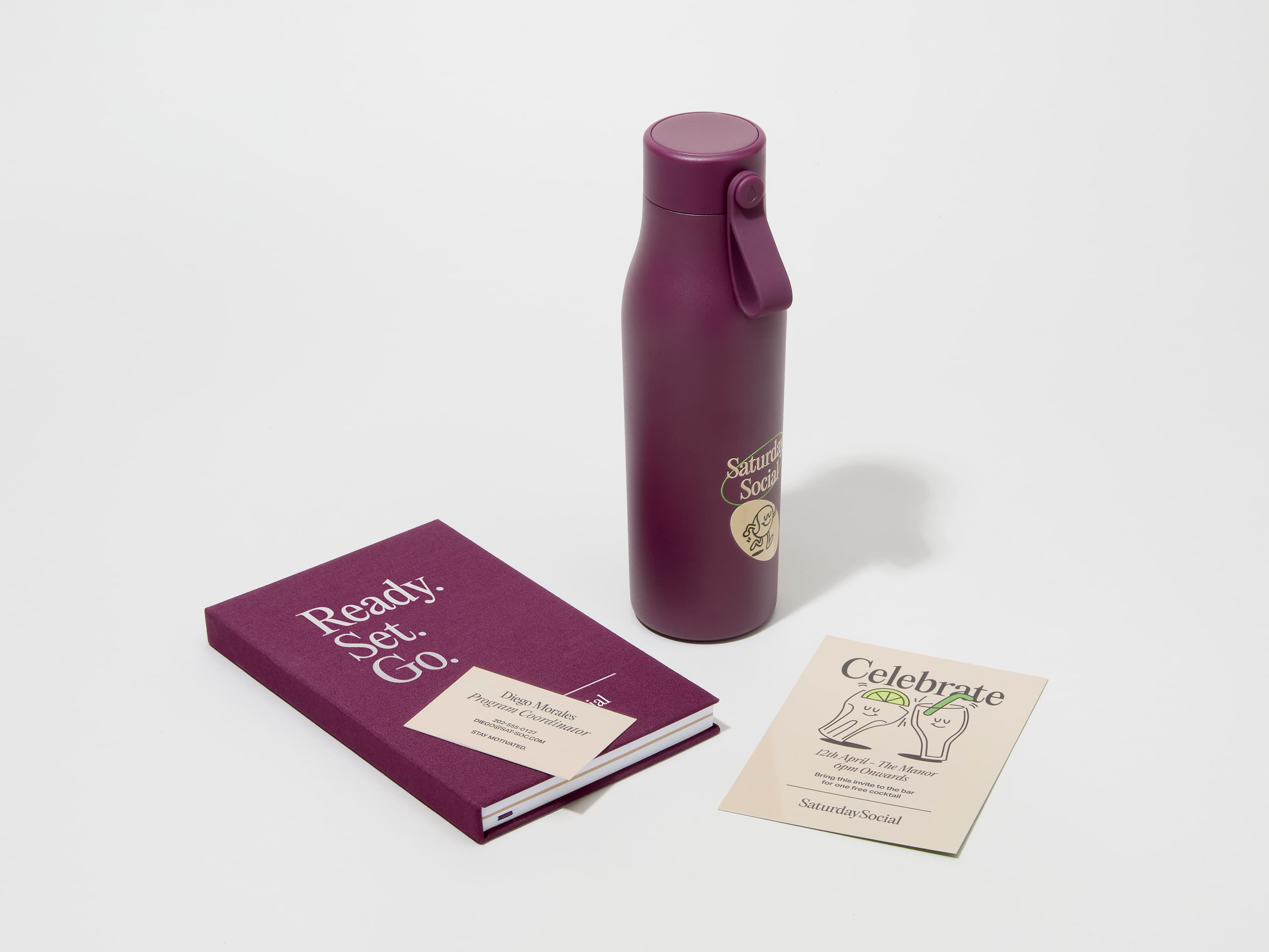 A collection of branded merchandise including a mulberry MOO water bottle with customized printing alongside a notepad, notebook and pen.