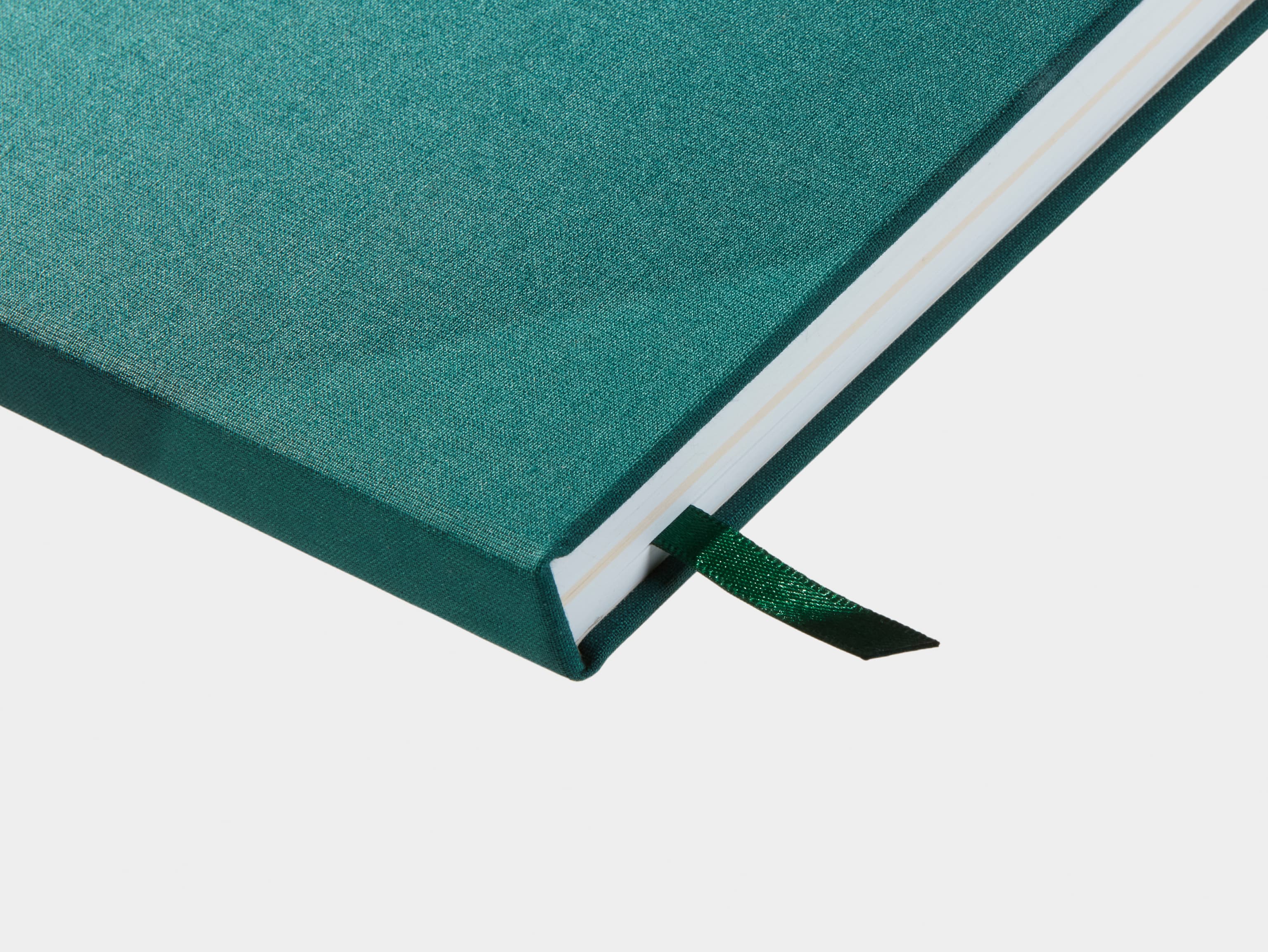 A close up of a closed Alpine Green Hardcover Notebook with a green ribbon sticking out