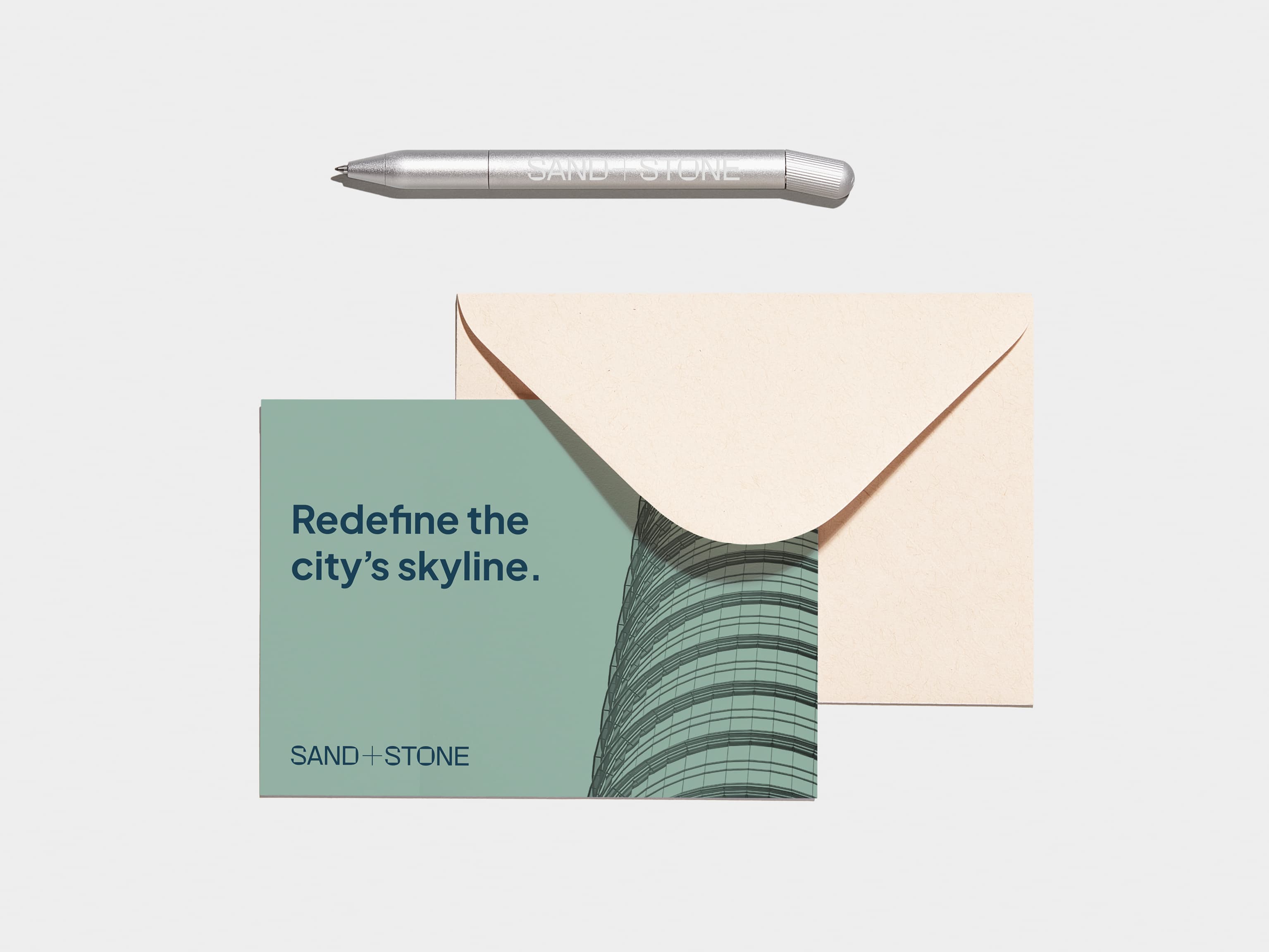 A custom aluminium pen placed above a post card and envelope.