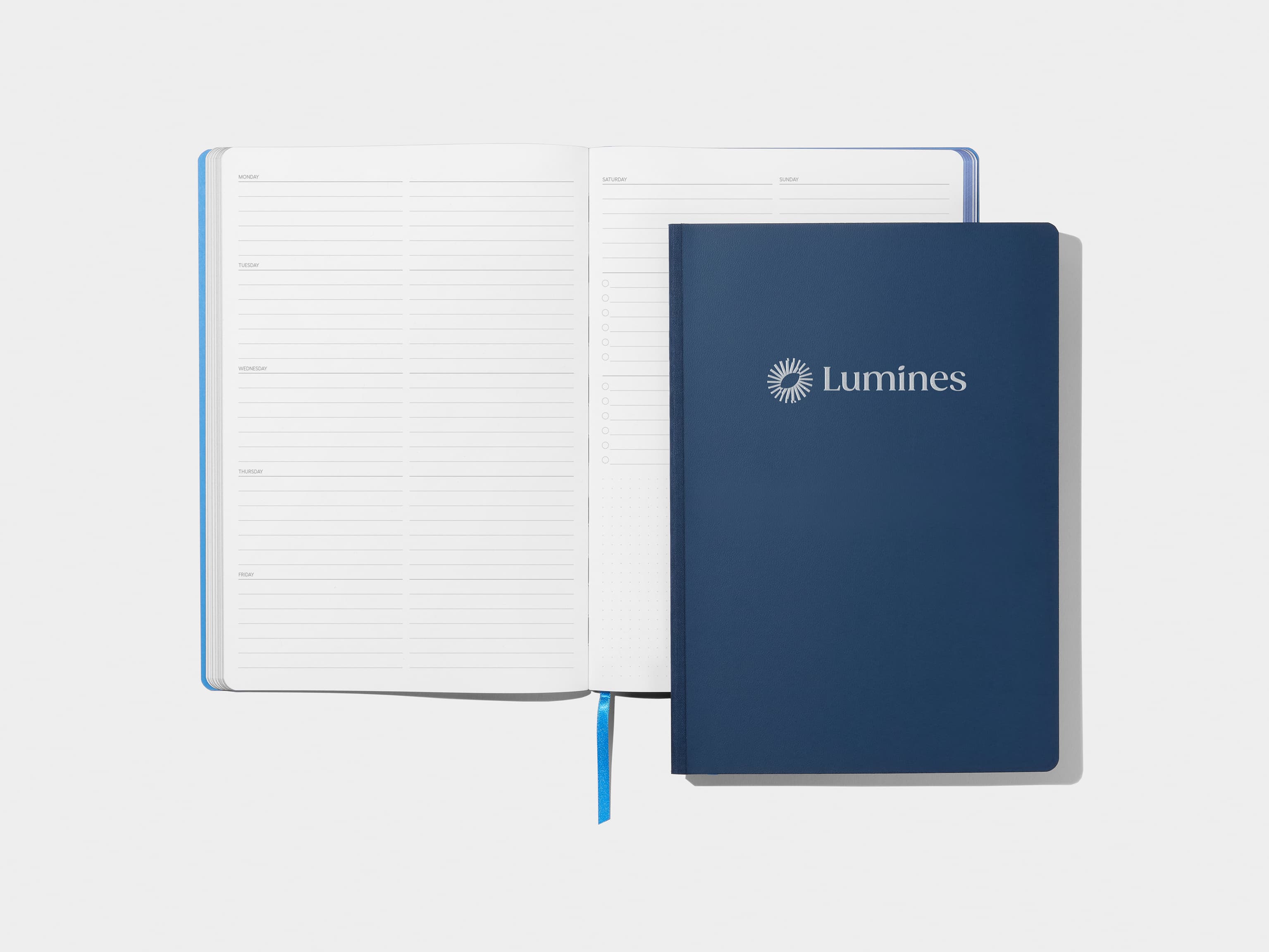 An open softcover planner with liner images with a midnight blue softcover planner positioned over the right page.