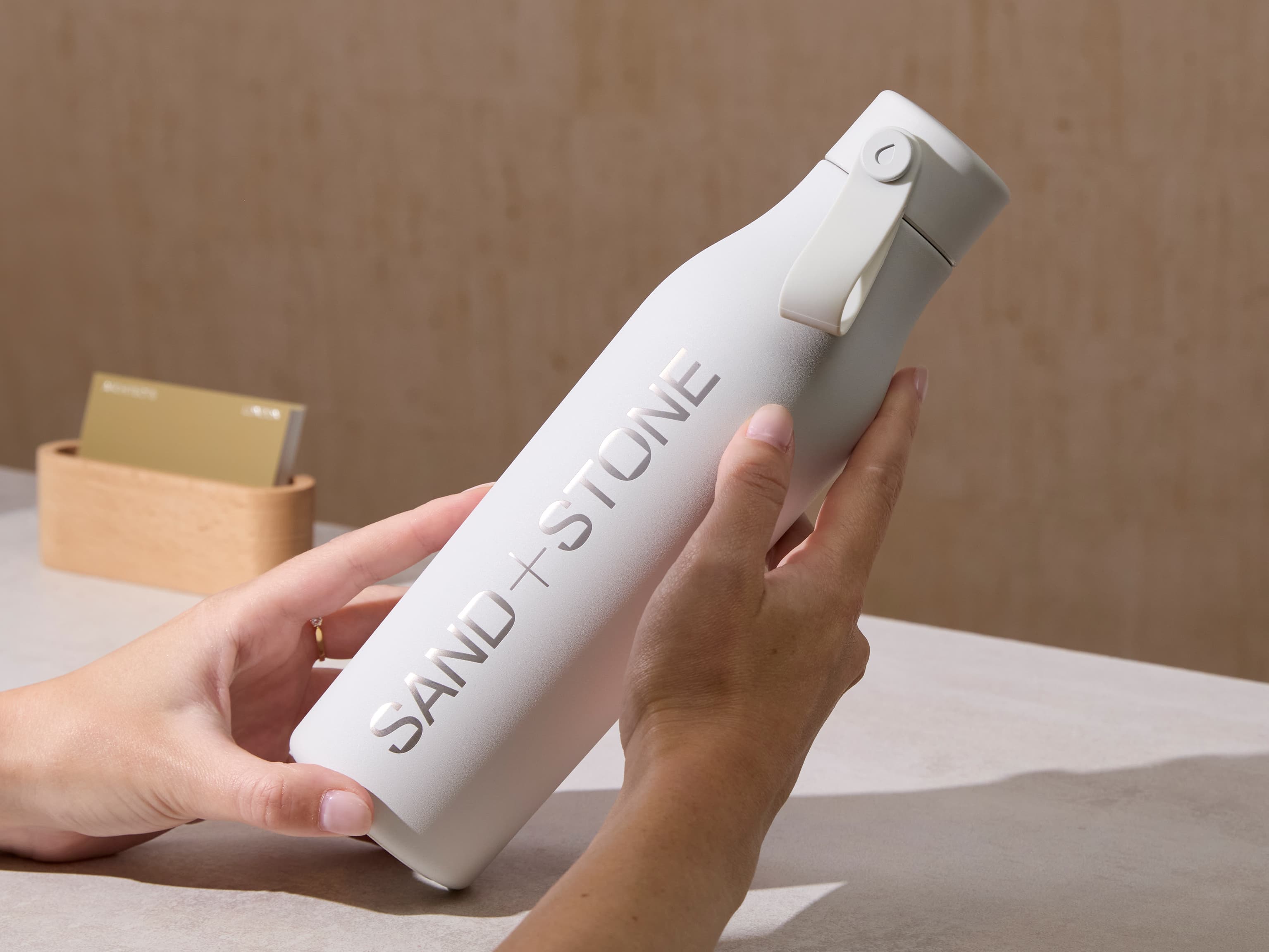 Person holding a cloud grey water bottle with custom silver branding.