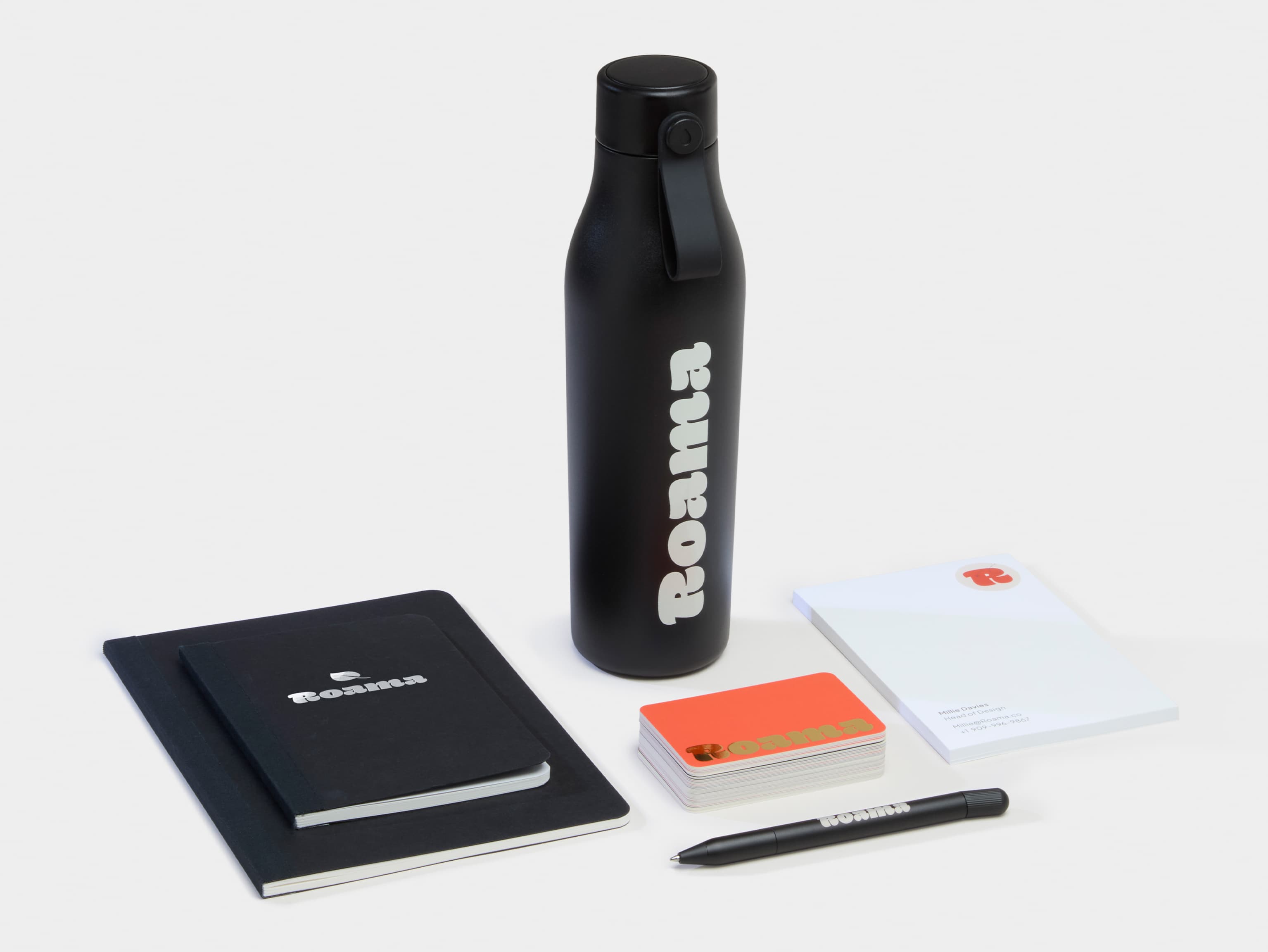 A collection of black Branded Merchandise including a water bottle, pen and notebooks.