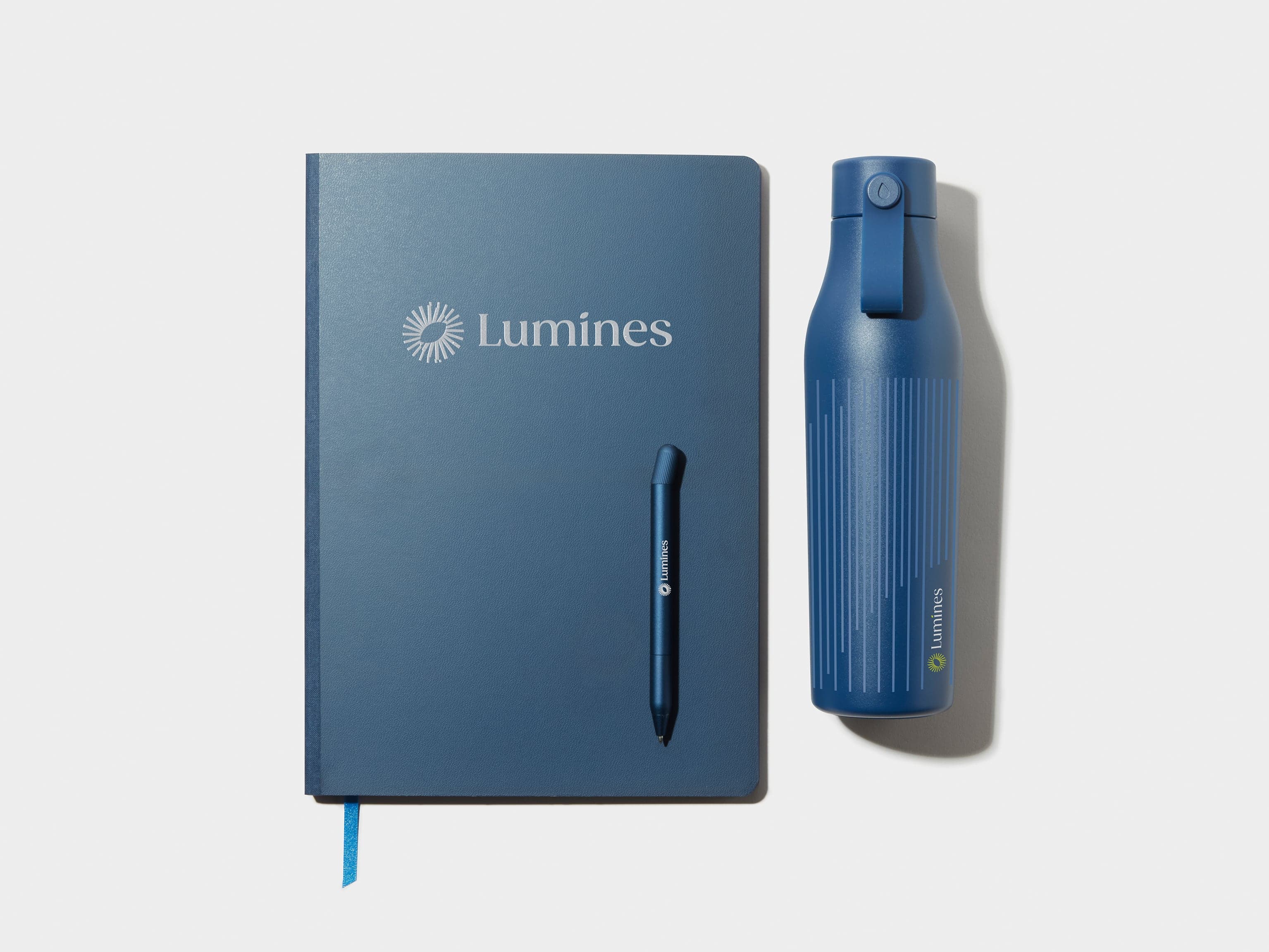 A collection of customised products including a blue water bottle, pen and softcover planner.