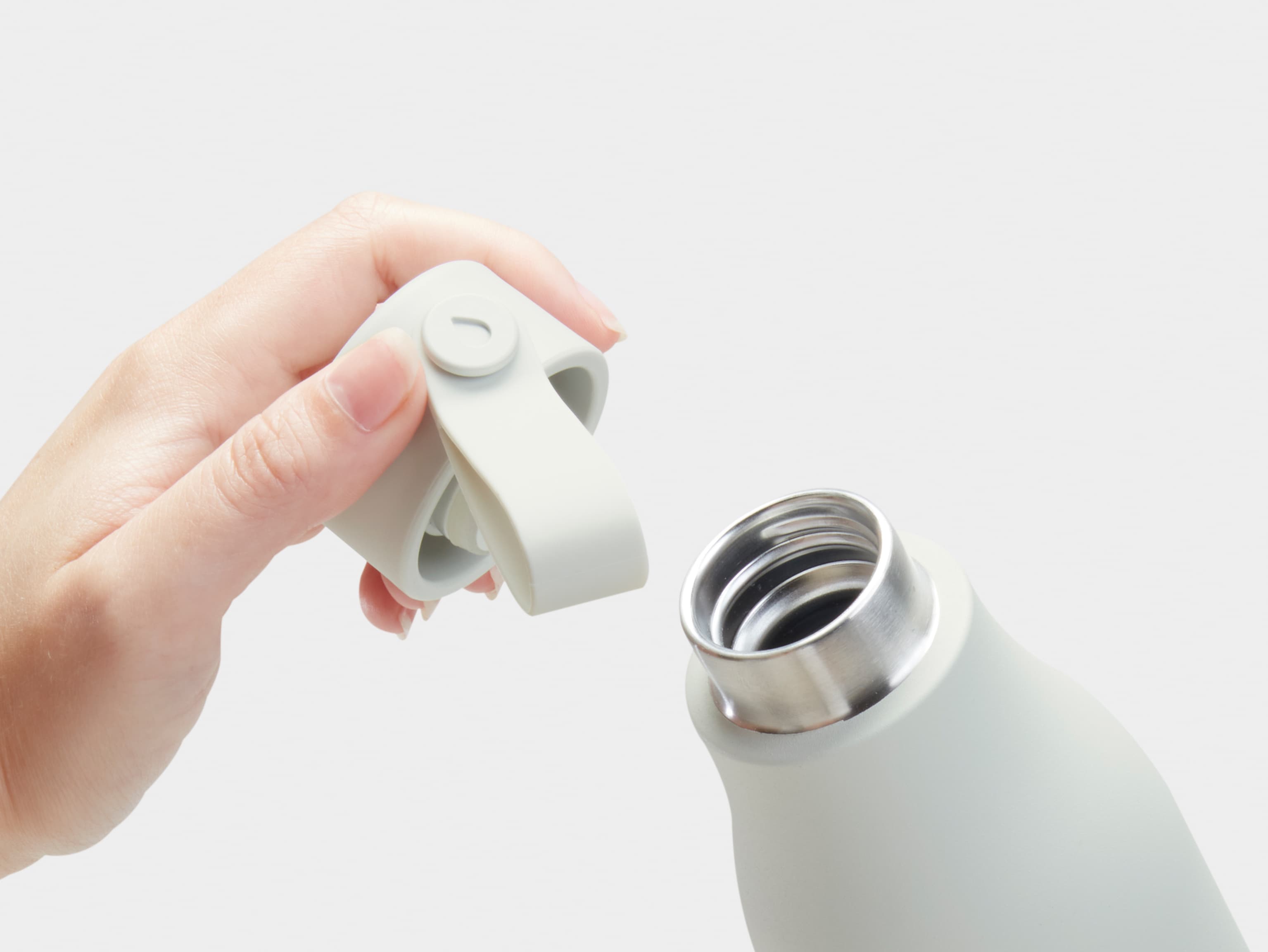 The top of a cloud grey water bottle with a person holding the lid.