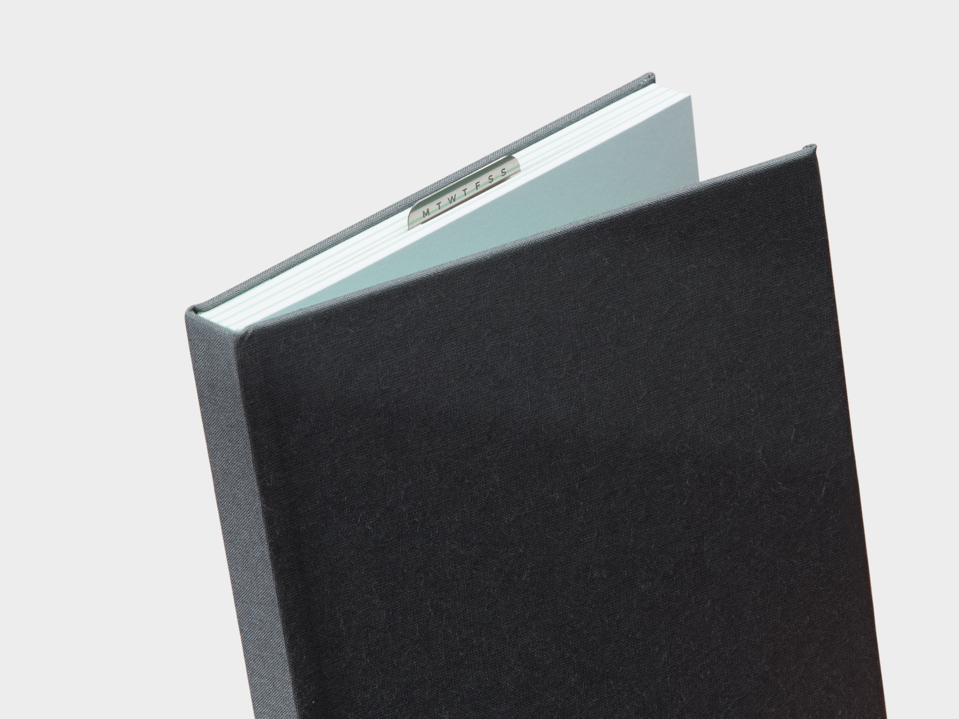 Half Opened Charcoal Grey  Cloth Planner with a silver clip sticking out