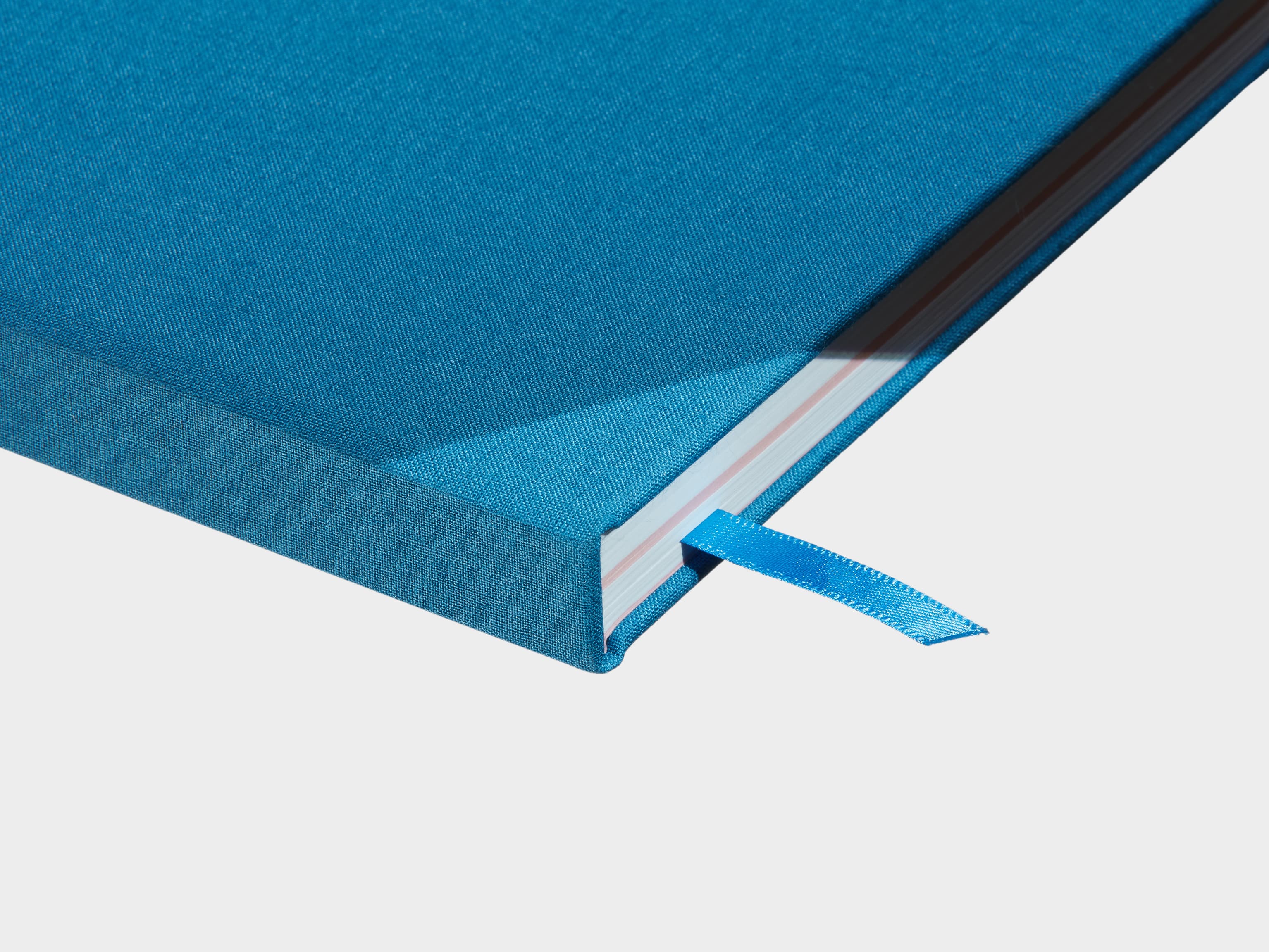 A close up of a closed Sky Blue Hardcover Notebook with a blue ribbon sticking out