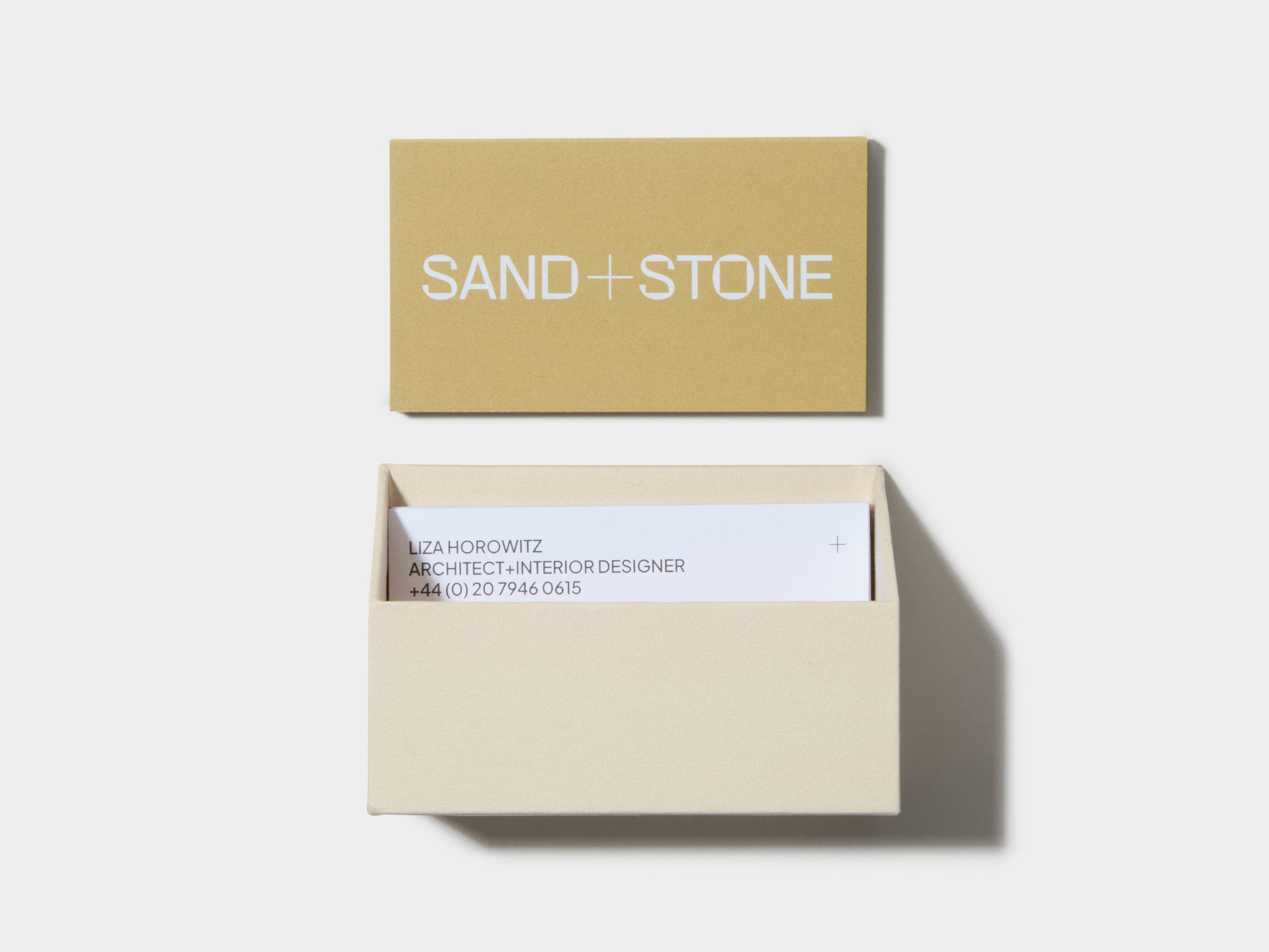 An open off white business card box with custom luxe business cards placed inside and above the box.