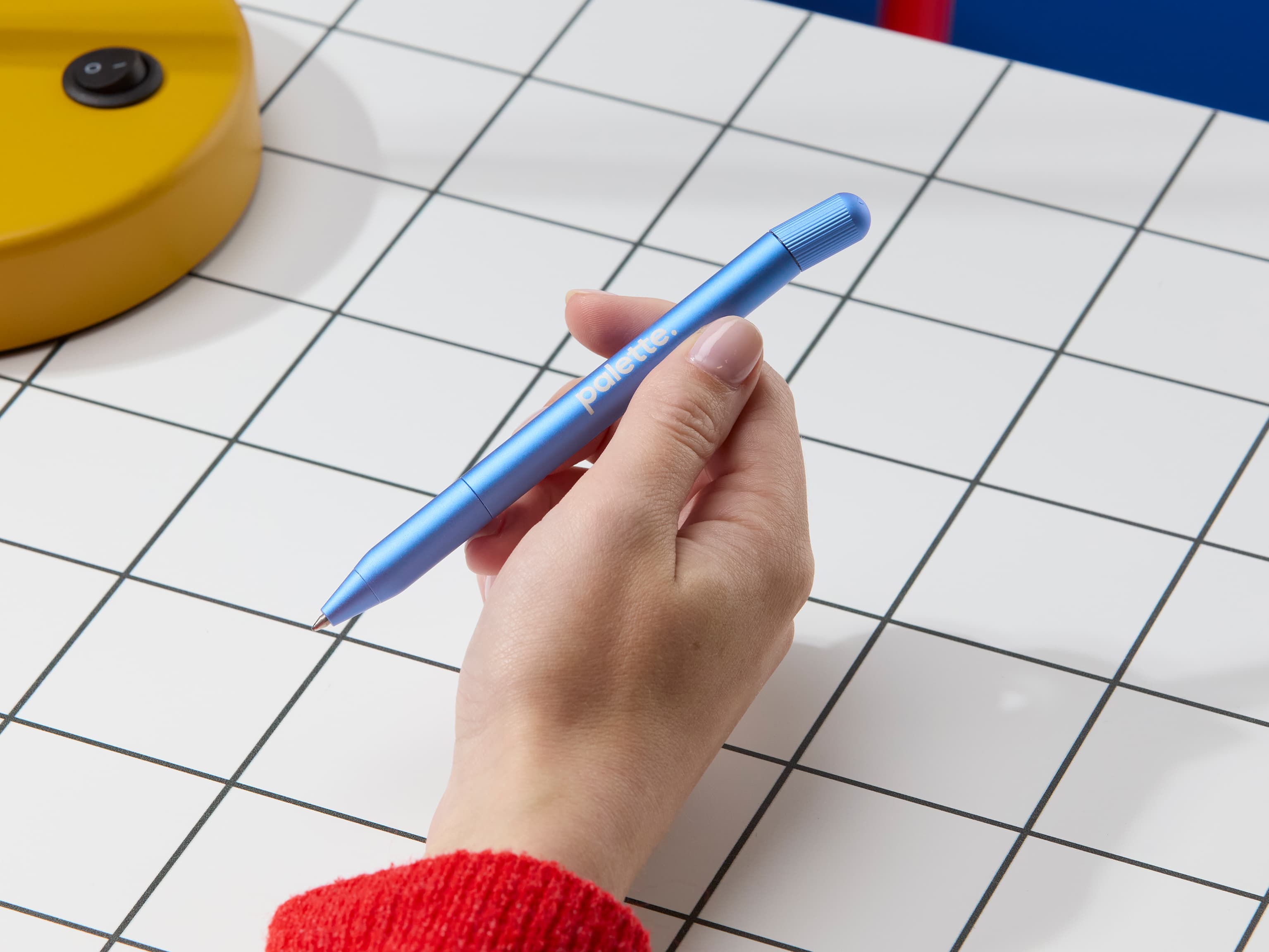 Person holding a blue pen with custom white branding.