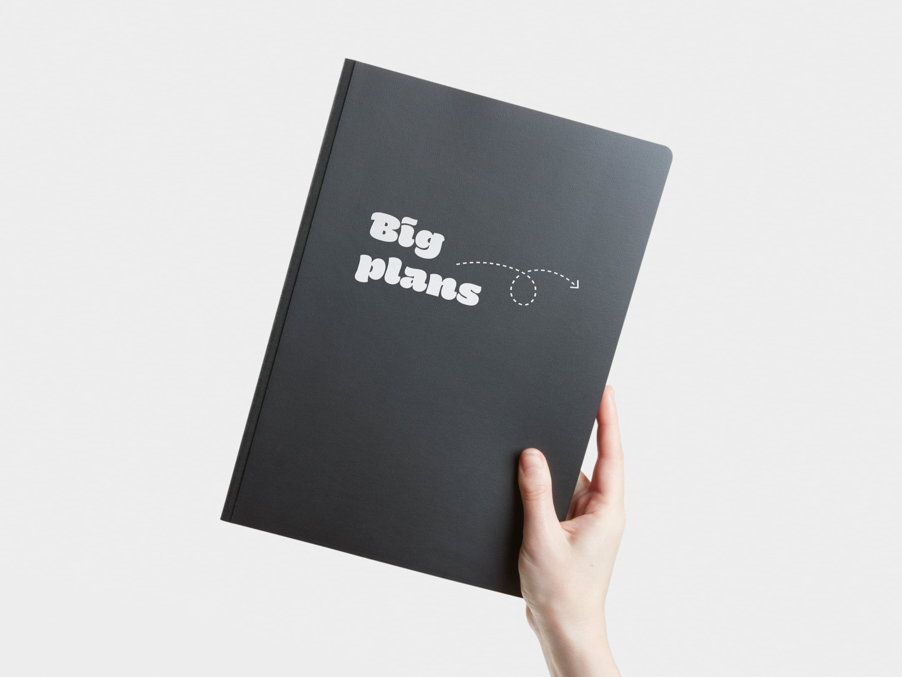 A hand holding a softcover planner with custom white branding.