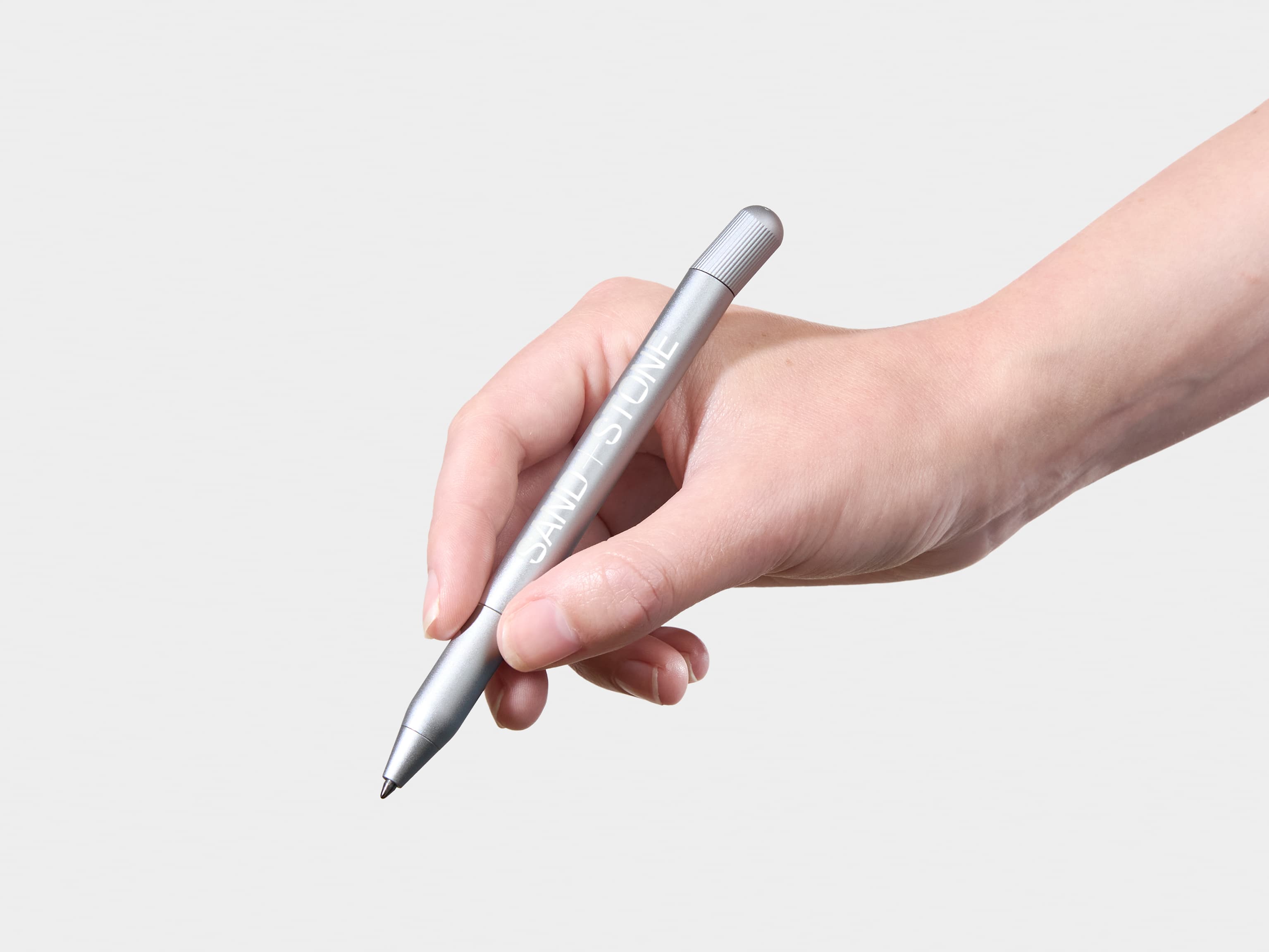 A person holding a aluminium pen with white custom branding.