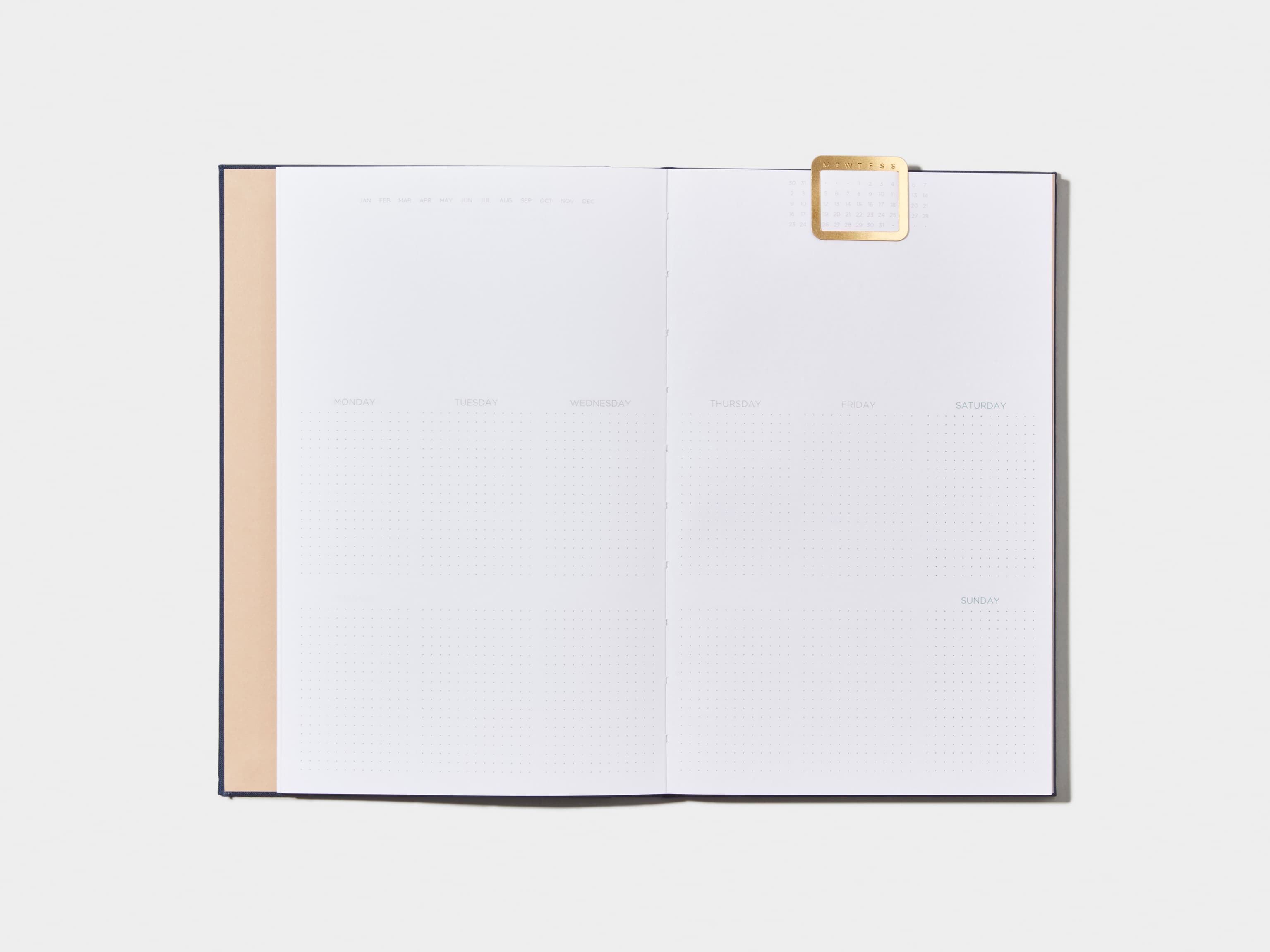 Opened Midnight Blue  Cloth Planner with a calendar page inside and a gold clip 