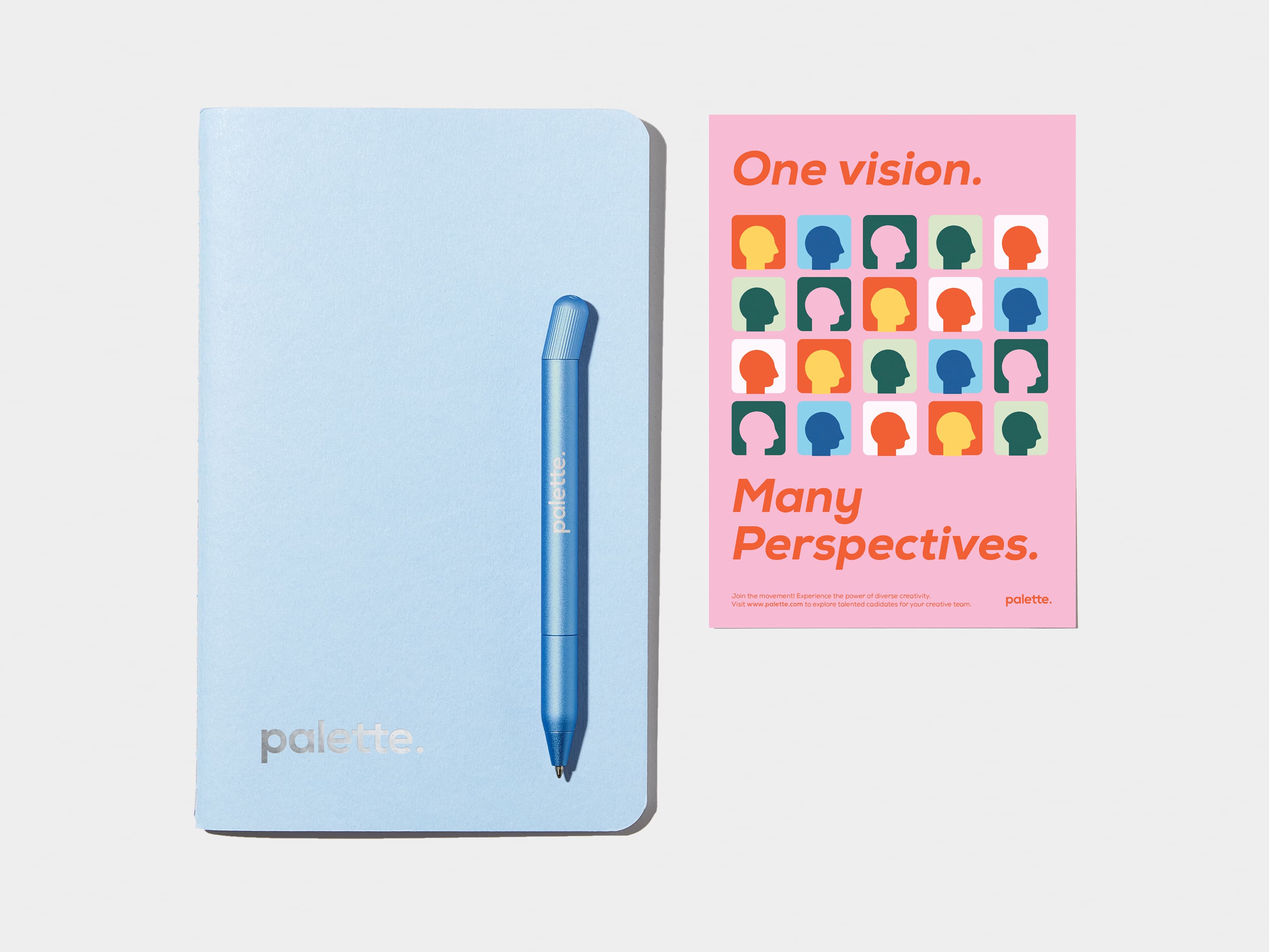 A custom blue pen placed on top of a custom blue notebook and next to a custom postcard.