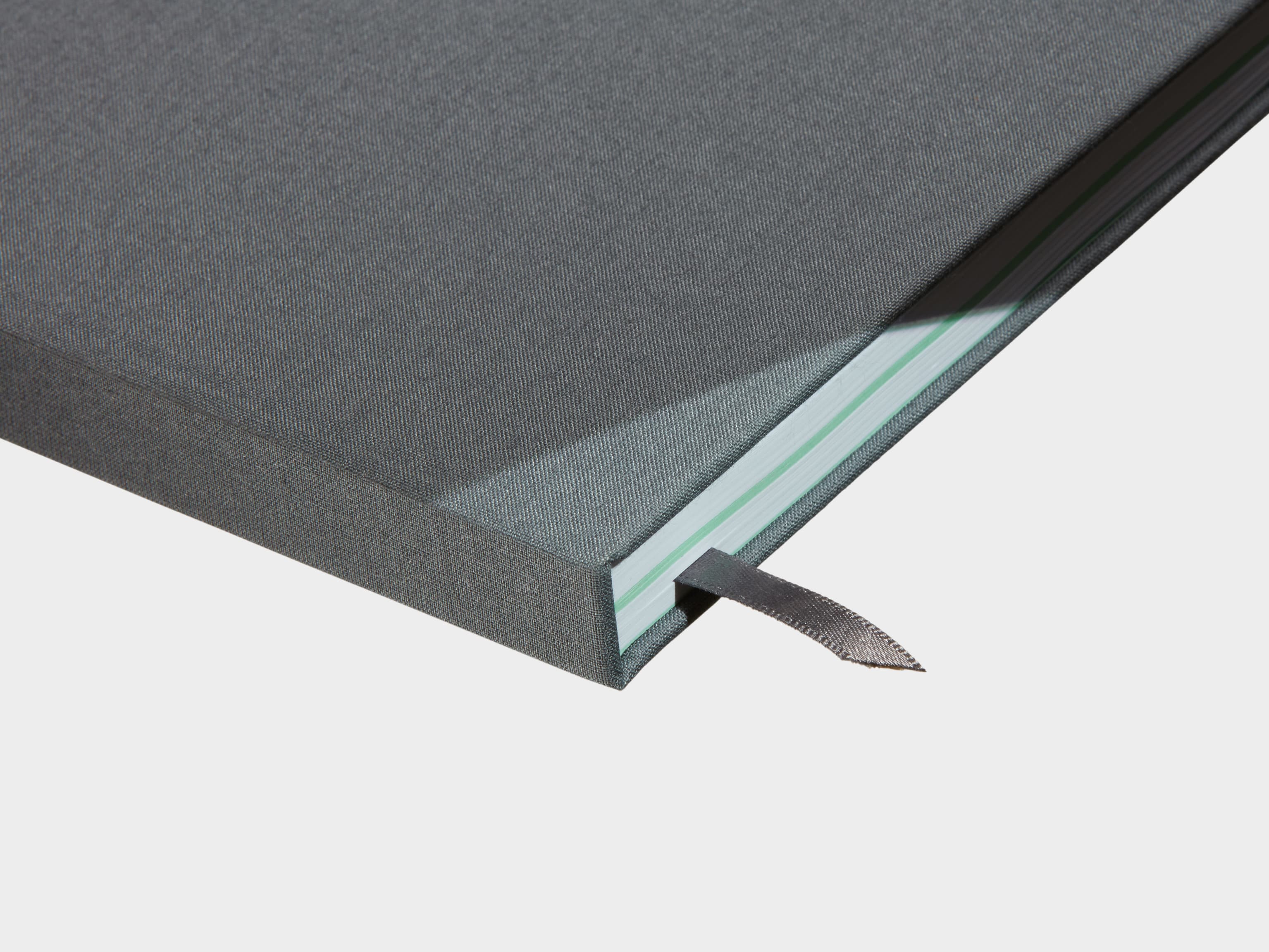 A close up of a closed Charcoal Grey Hardcover Notebook with a grey ribbon sticking out