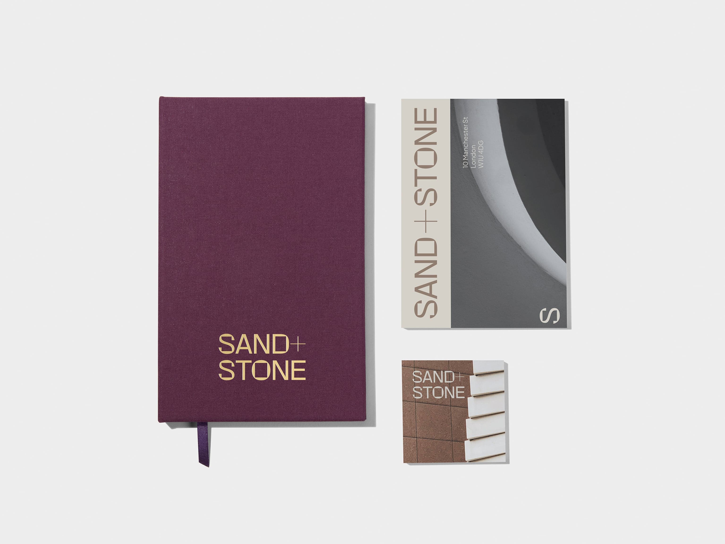 A collection of products displayed including a mulberry hardcover notebook and two print products.