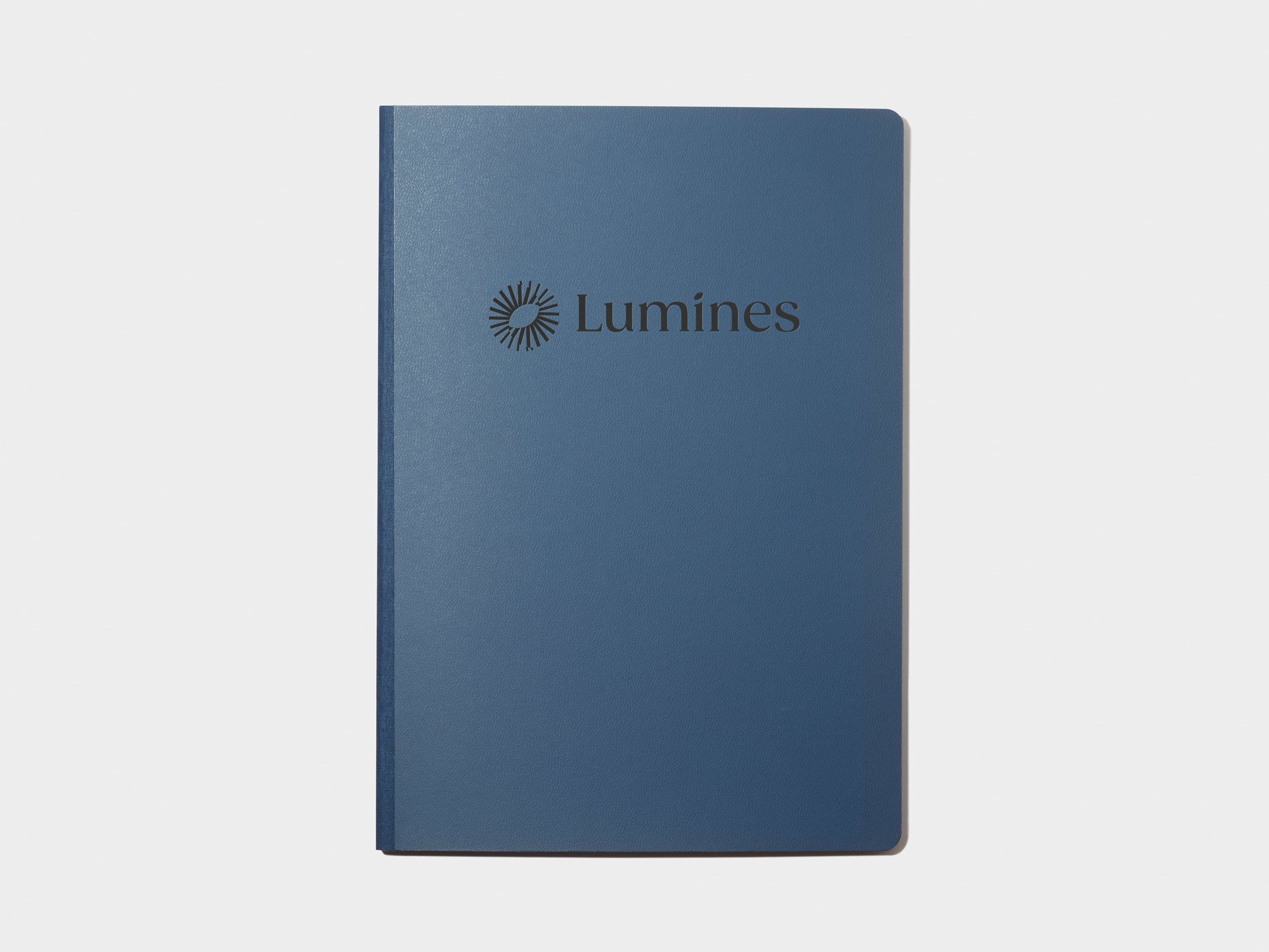 A blue softcover planner with custom branding in black foil.