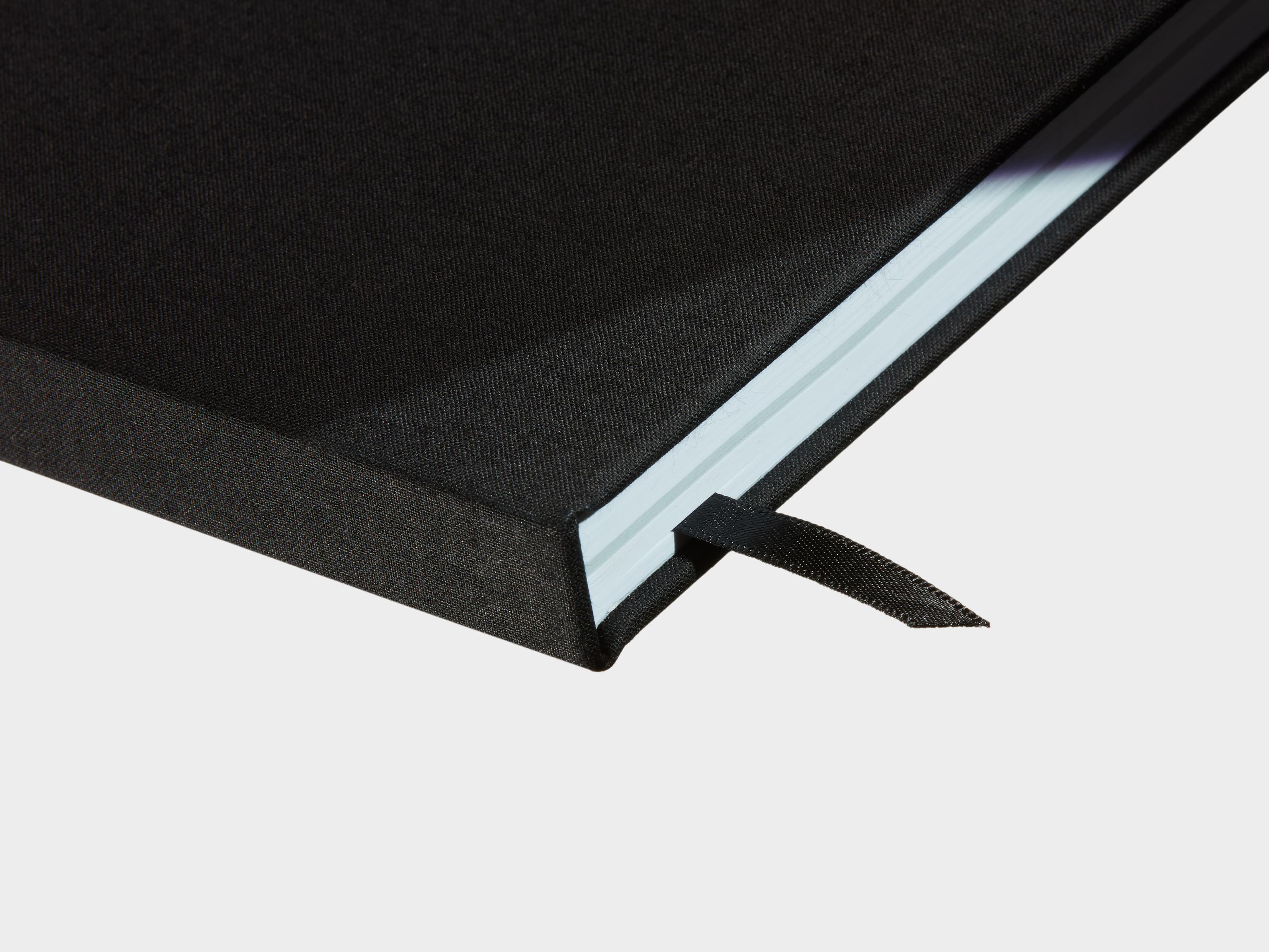 A close up of a closed Jet Black Hardcover Notebook with a black ribbon sticking out