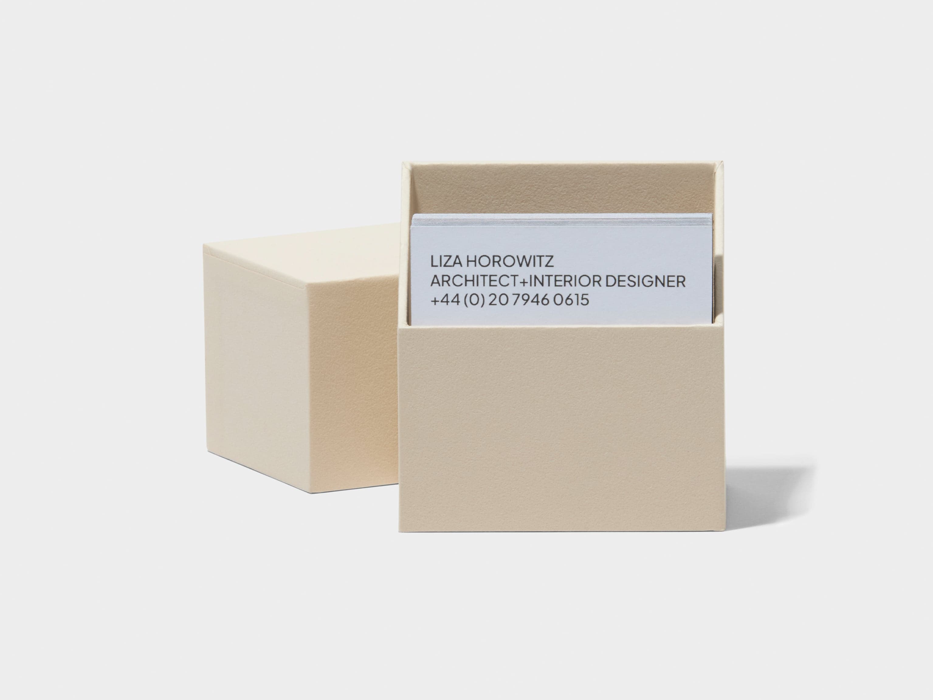 A square off white business card box open with white customised luxe business cards placed inside.