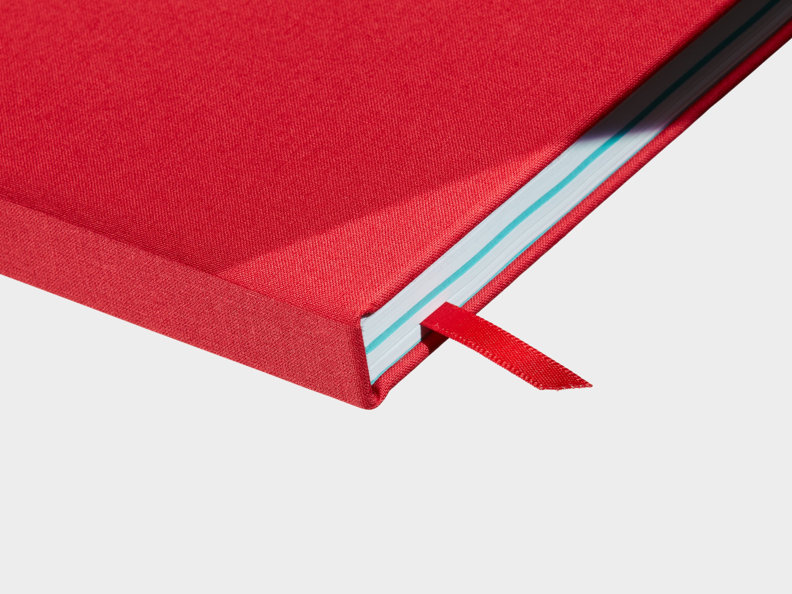 A close up of a closed Berry Red Hardcover Notebook with a red ribbon sticking out