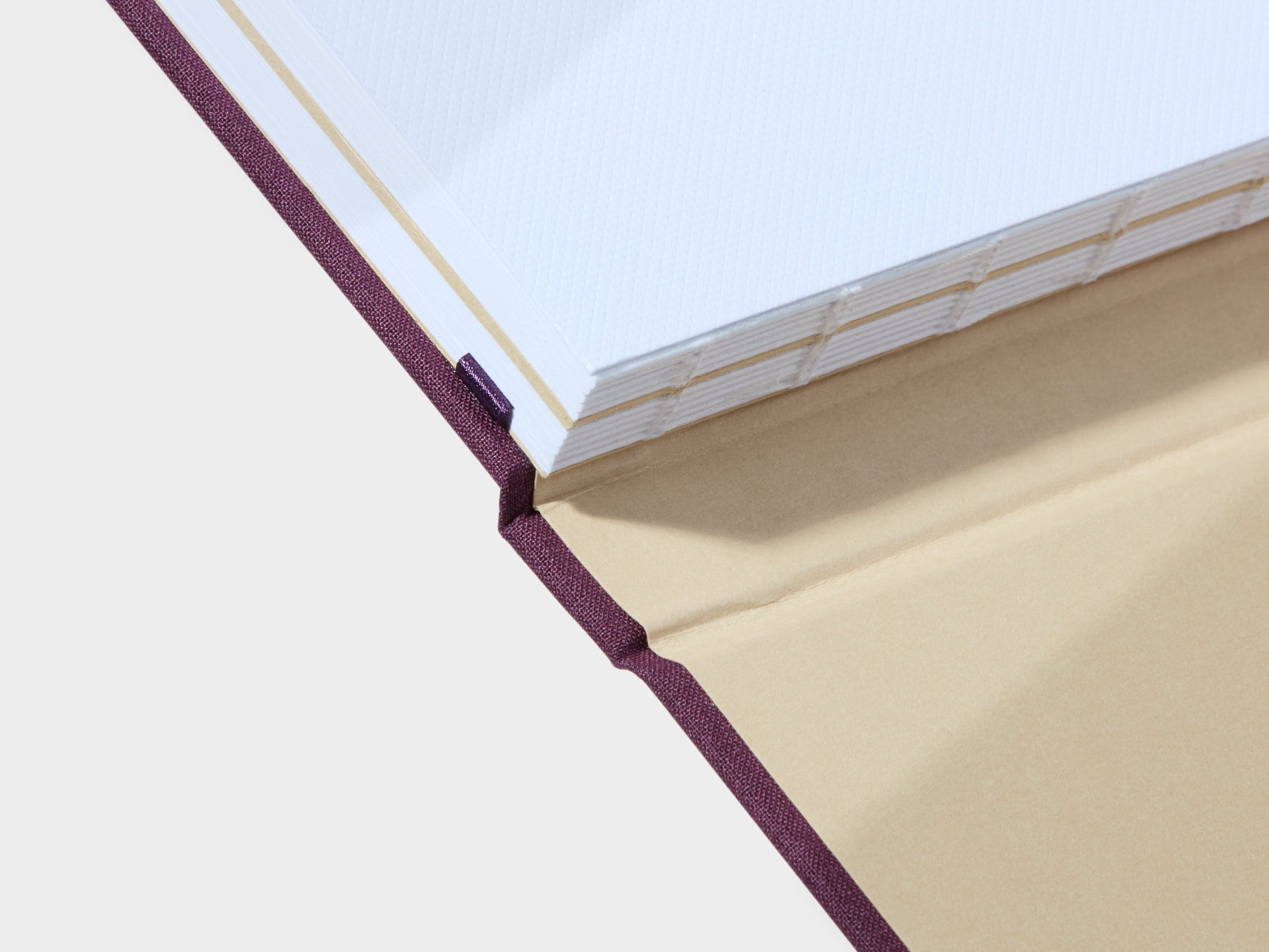 Detail image of the swiss binding design on the spine of a mulberry coloured hardcover notebook.