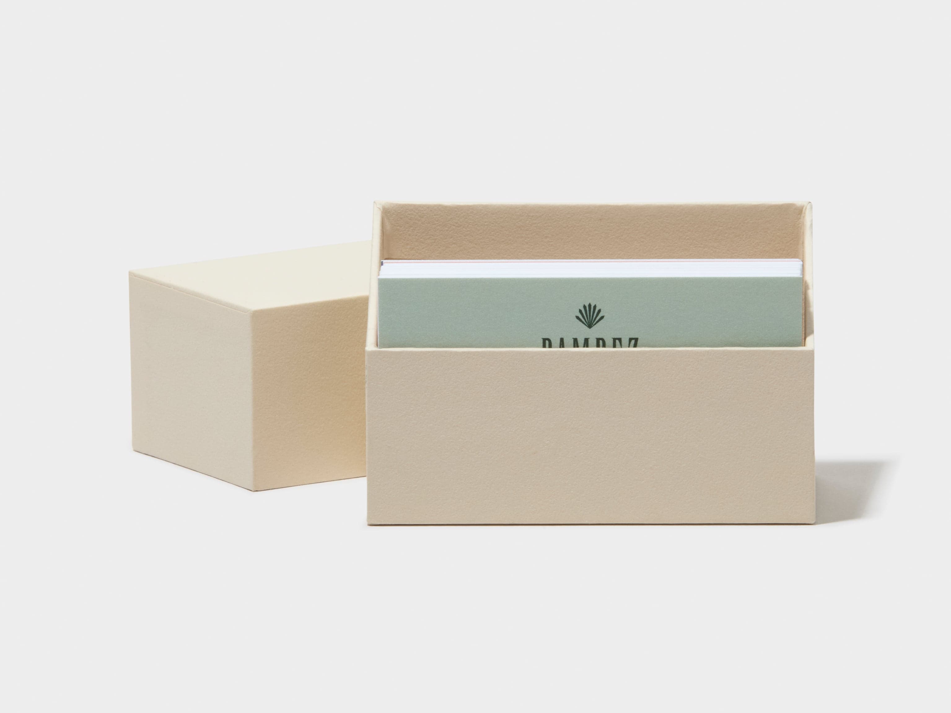 An off white business card box with customised luxe business cards placed inside.