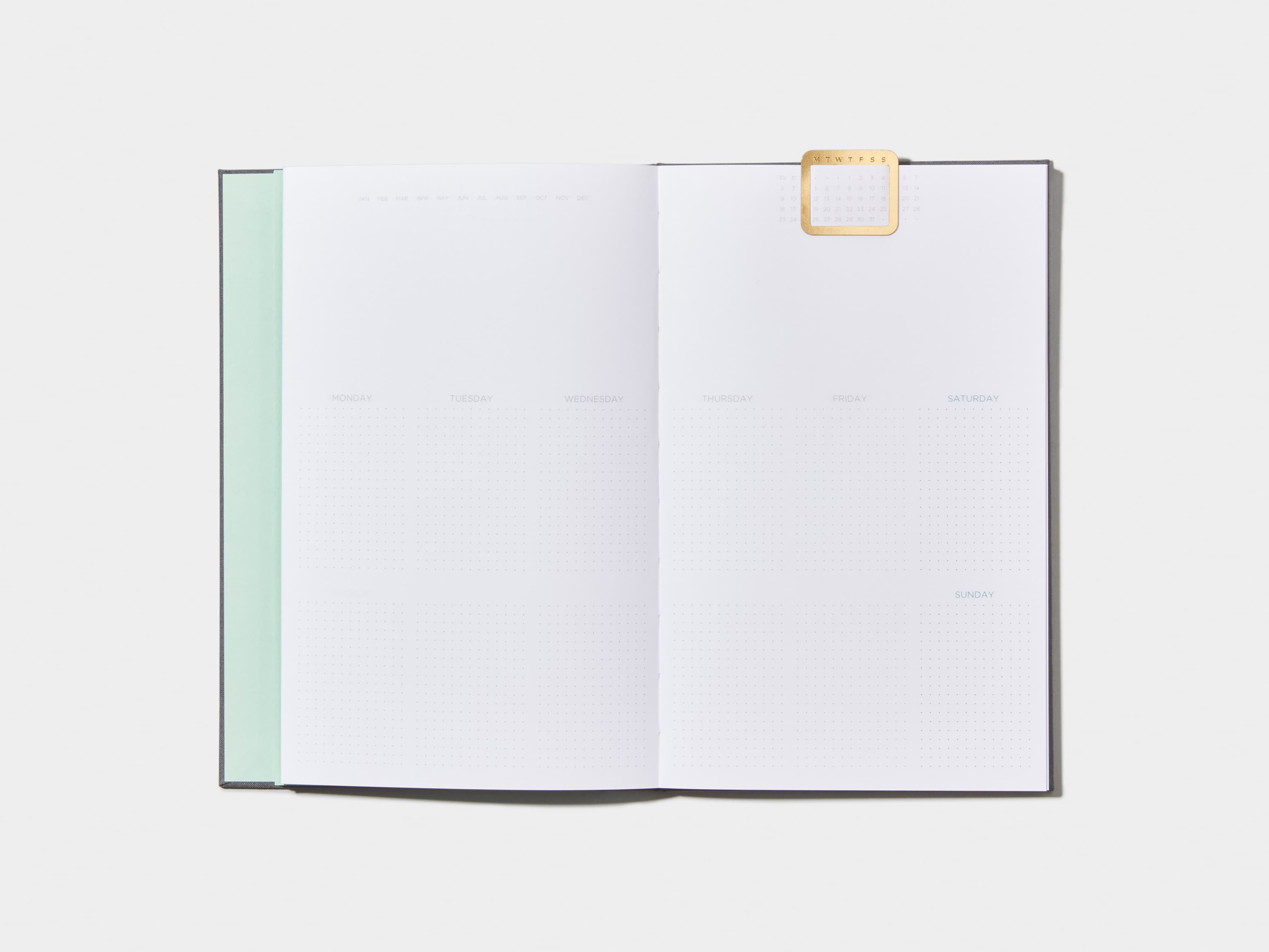 Opened Charcoal Grey  Cloth Planner with a calendar page inside and a gold clip 