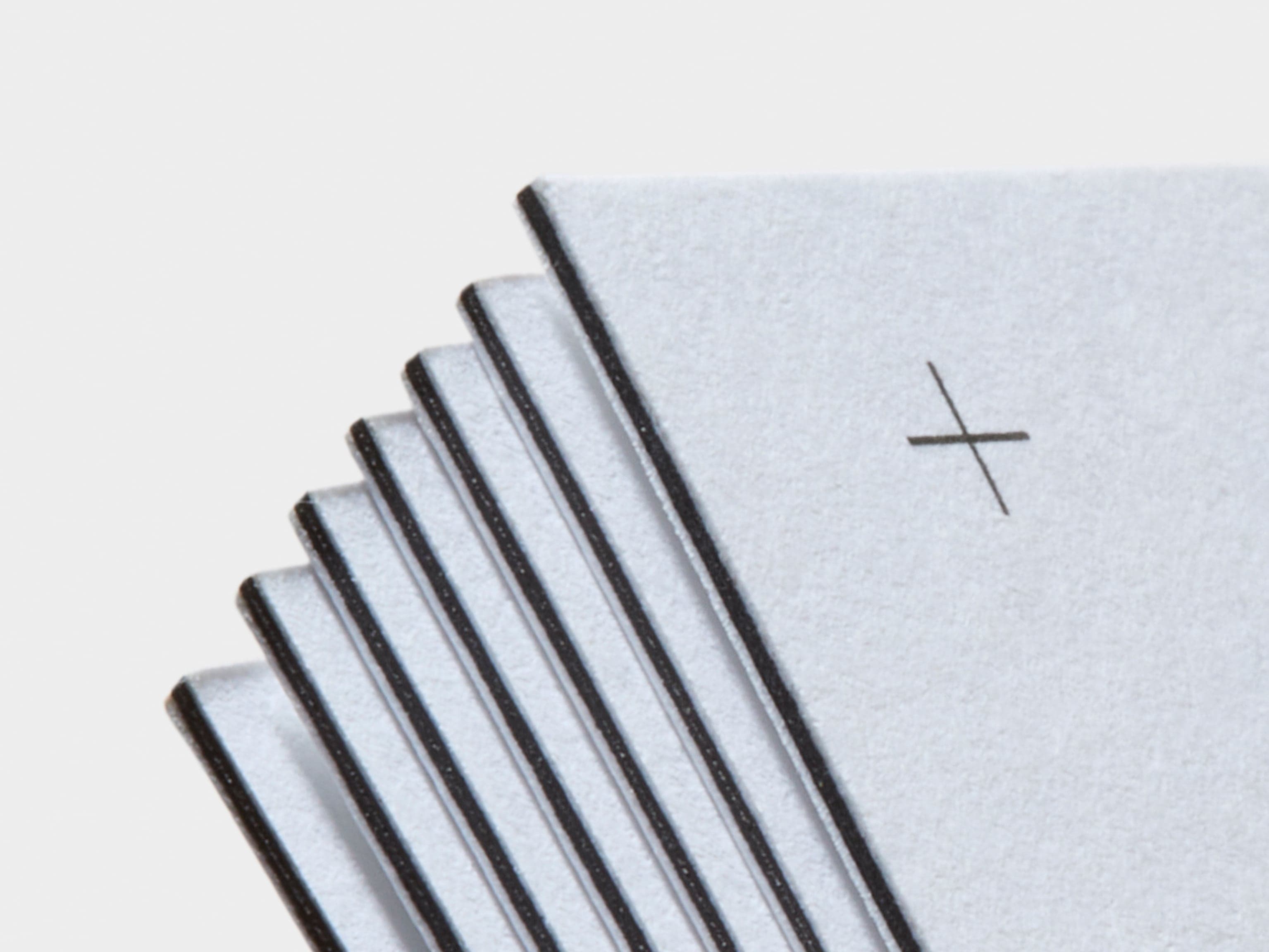 A detail image of the corners of white luxe business cards with black detailing.