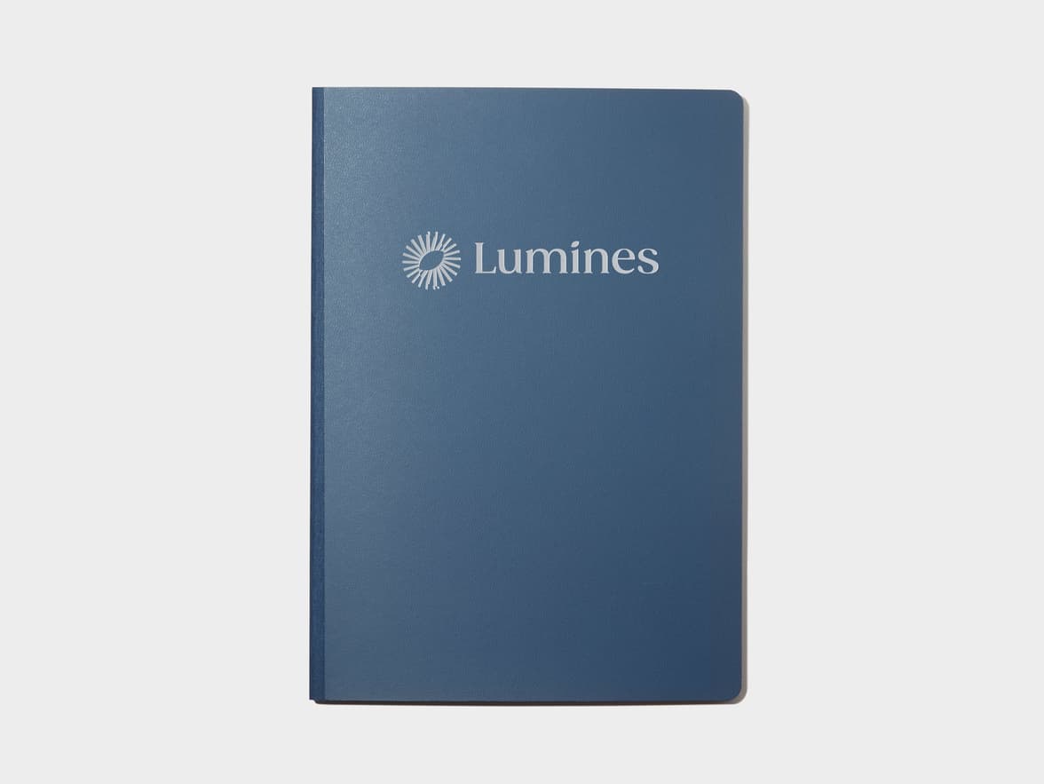 A blue softcover planner with custom branding in silver foil.