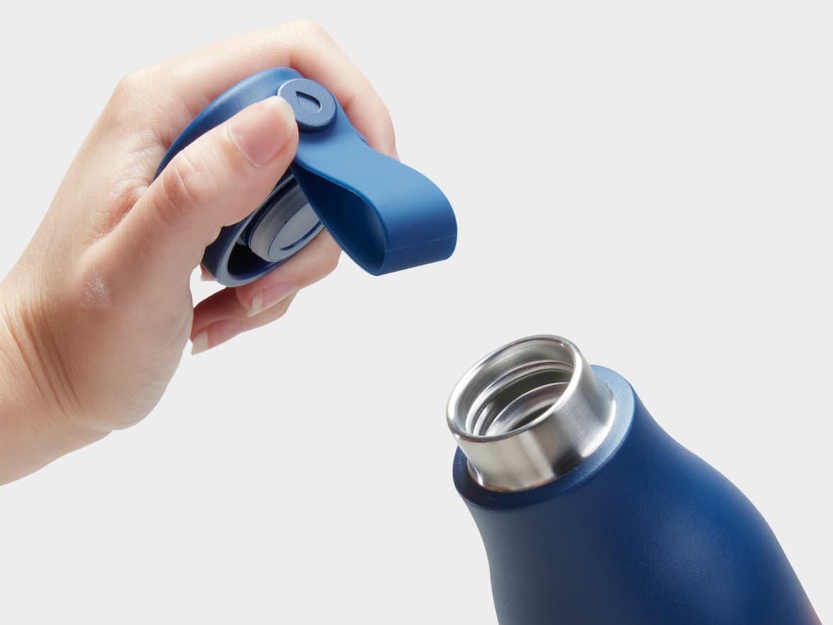 The top of a blue water bottle and a person holding the lid.