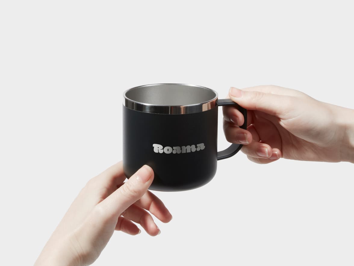 A person holding a customised black insulated mug with two hands.