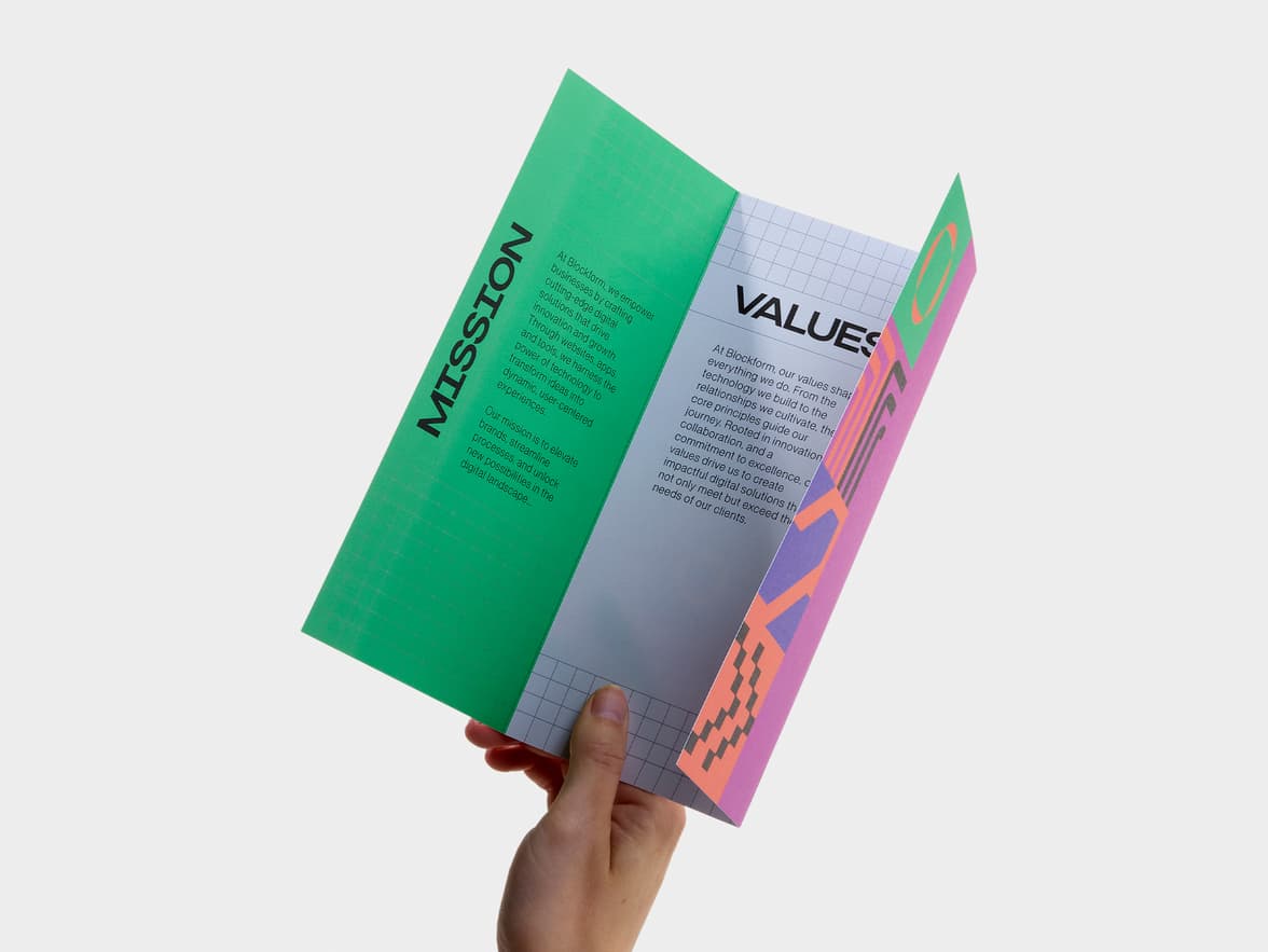 Hand holding an opened a tri-fold matte paper brochure.