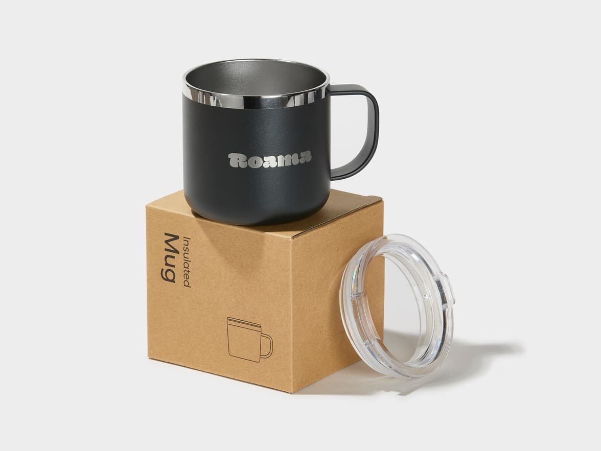 A black insulated mug with customized engraving placed on top if its packaging.